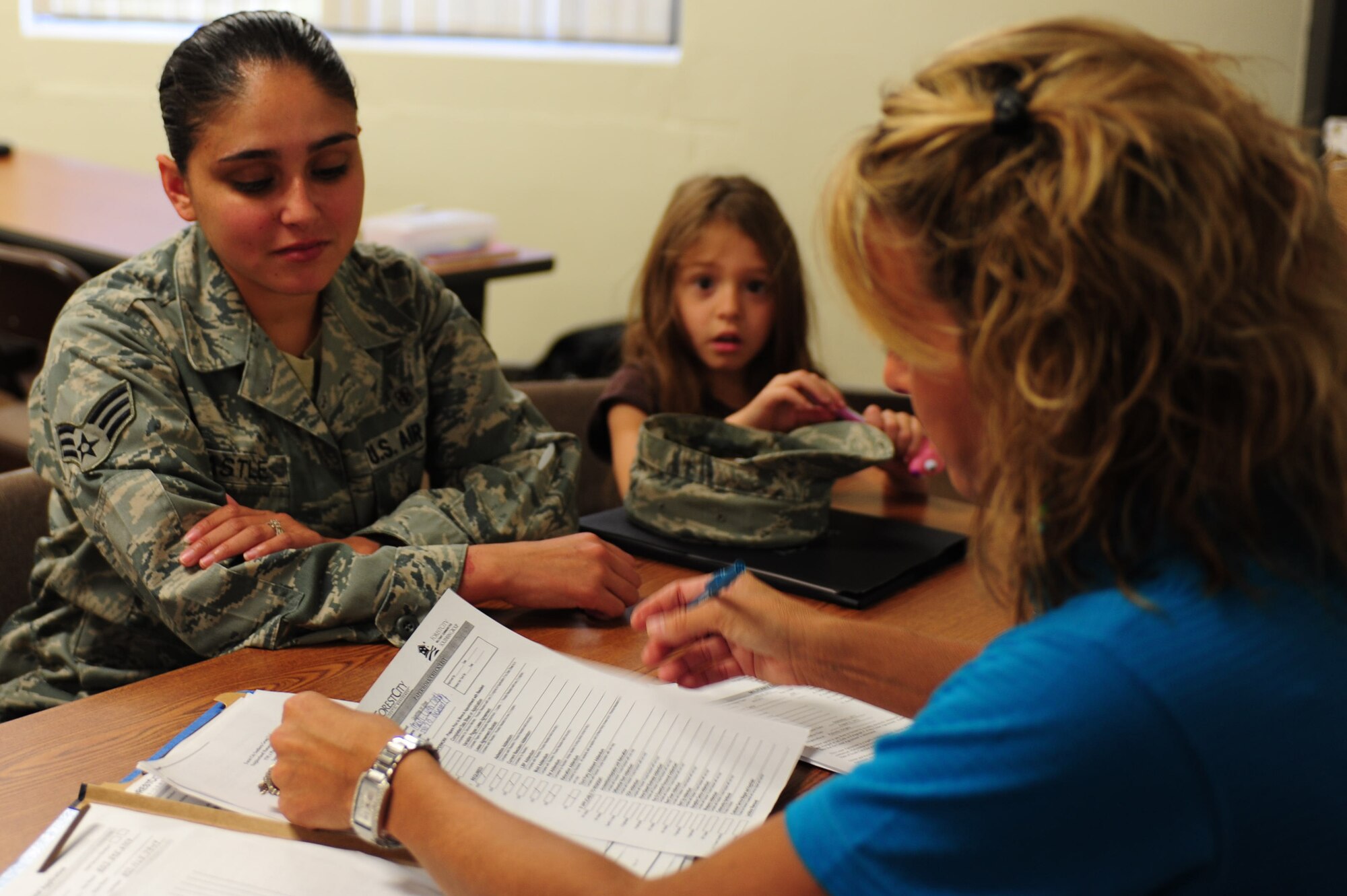 Senior Airman MartiLynn Castle, 20th Medical Group medical logistics technician, signs her new resident lease for privatized housing with Forest City as her daughter watches at the community center, Shaw Air Force Base, S.C., July 21, 2011. The all-day event allowed Shaw family housing residents to sign their new leases for privatized housing. This marked the first time Forest City had the opportunity to meet and serve Shaw family housing residents. (U.S.  Air Force photo by Senior Airman Alexandria Mosness)