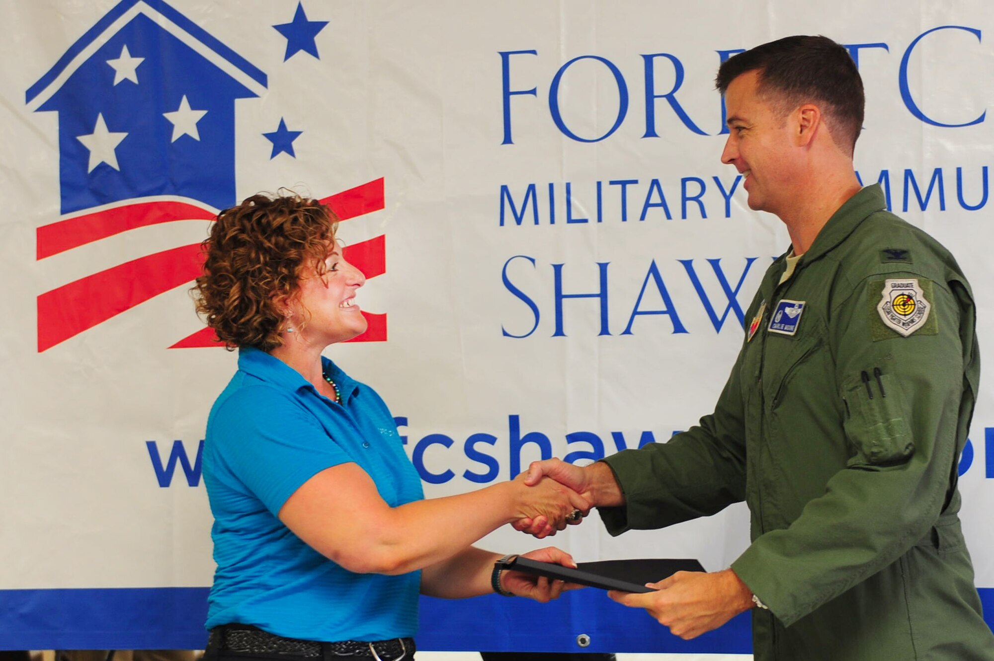 Jamie Seehafer, Forest City southern group general manager, shakes hands with U.S. Air Force Col. Charlie Moore, 20th Fighter Wing commander, after signing his new resident lease for privatized housing with Forest City at the community center, Shaw Air Force Base, S.C., July 21, 2011. The all-day event allowed Shaw family housing residents to sign their new leases for privatized housing. This marked the first time Forest City had the opportunity to meet and serve Shaw family housing residents. (U.S.  Air Force photo by Senior Airman Alexandria Mosness)