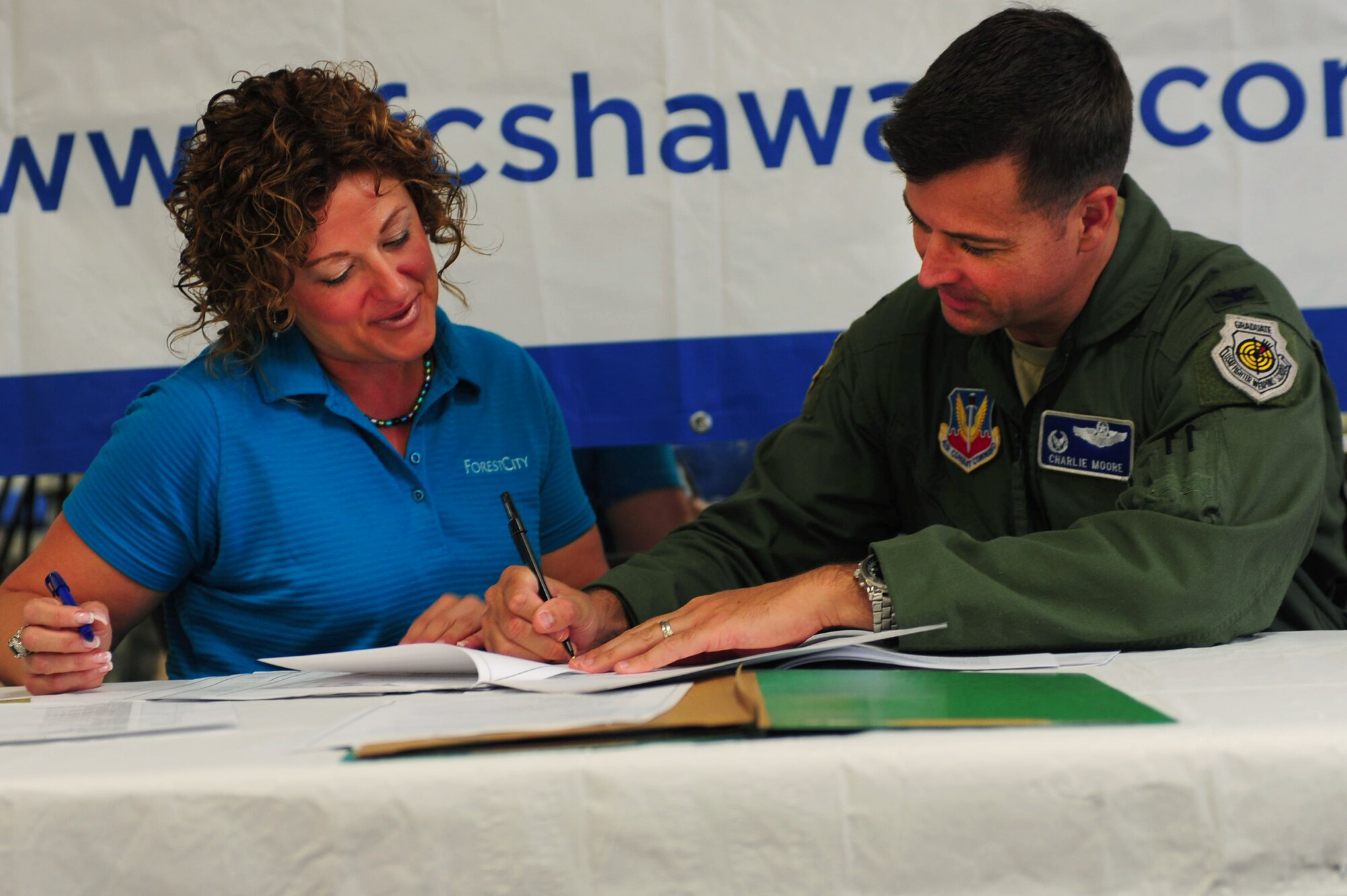 Jamie Seehafer, Forest City southern group general manager, assists U.S. Air Force Col. Charlie Moore, 20th Fighter Wing commander, as he signs his new resident lease for privatized housing with Forest City at the community center, Shaw Air Force Base, S.C., July 21, 2011. The all-day event allowed Shaw family housing residents to sign their new leases for privatized housing. This marked the first time Forest City had the opportunity to meet and serve Shaw family housing residents. (U.S.  Air Force photo by Senior Airman Alexandria Mosness)