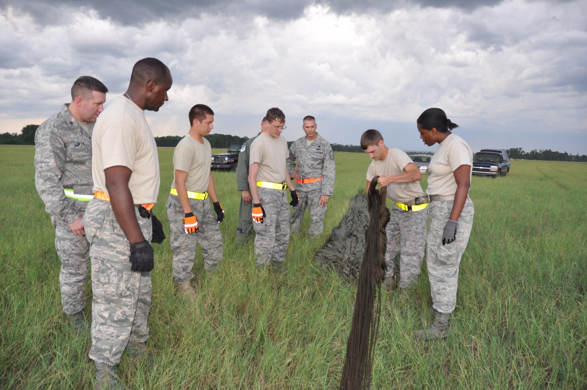 Tech. Sgt. Neal Moore, second from right, demonstrates the proper technique for field packing a parachute to new members of the 25th Aerial Port Squadron.