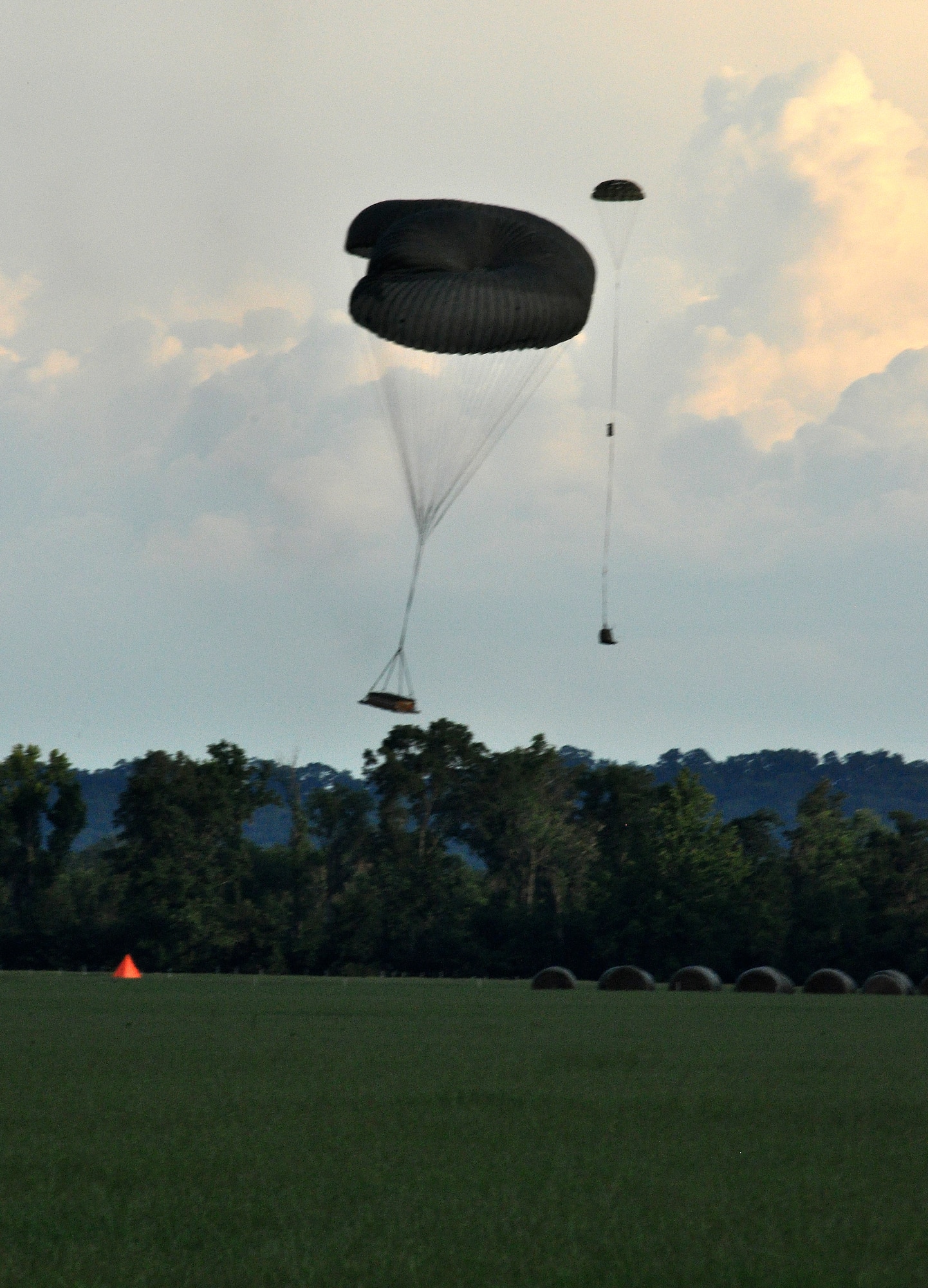 A 3,700-pound training platform suspended from two 64-inch diameter parachutes are shown prior to landing a few yards from the target.