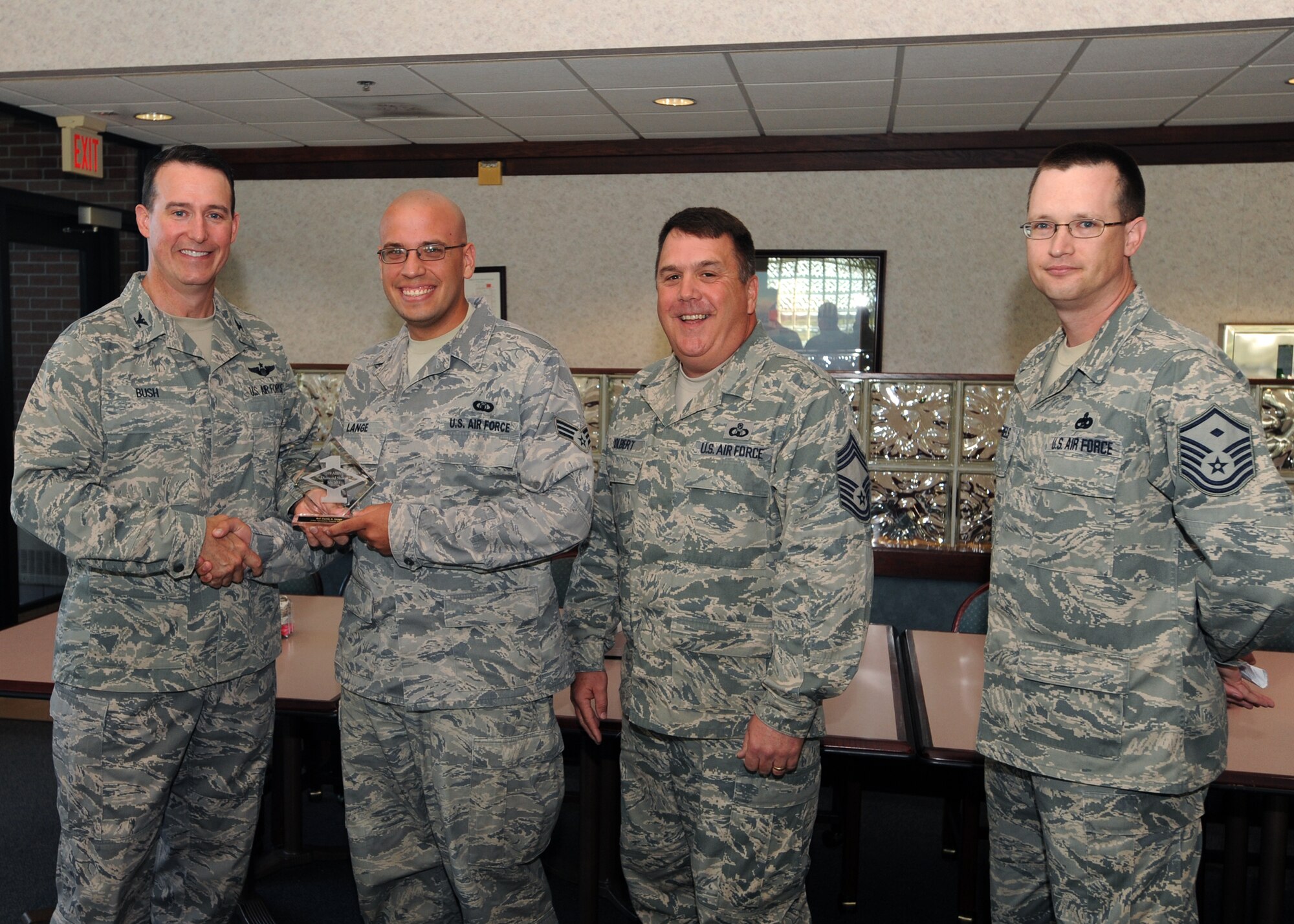 Col. Tim Bush, 319th Air Base Wing commander, presents Senior Airman Curtis Lange, 319th Operations Support Squadron, with a Diamond Sharp Award July 21 at Airey Dining Facility here, accompanied by Chief Master Sgt. Donald Colbert, 319th Operations Support Squadron, and Master Sgt. Patrick Michaels, 319th Comptroller Squadron first sergeant. The Diamond Sharp Award is given to those Airmen who epitomize service before self and strive for excellence at work and off duty. (U.S. Air Force photo by Staff Sgt. Suellyn Nuckolls)