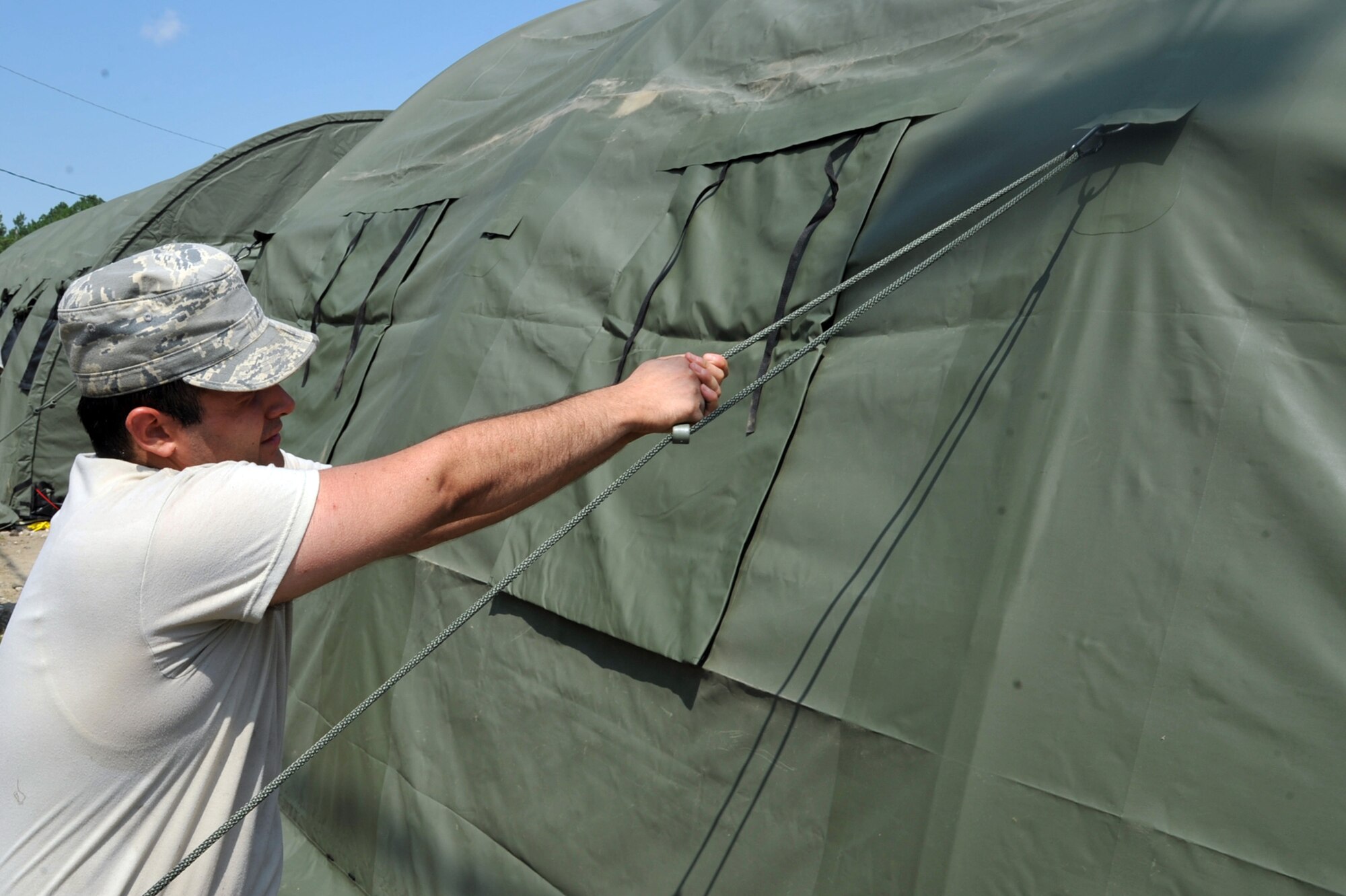 SEYMOUR JOHNSON AIR FORCE BASE, N.C.- Airman 1st Class Andres Olaya-Gonzalez ties down a rapid deployment system tent while setting up for the operational readiness exercise here July 11, 2011. Airmen put up these tents to simulate being in a deployed setting for the exercise. Olaya-Gonzalez is a 4th Fighter Wing military justice paralegal and a native of Boston. (U.S. Air Force photo by Senior Airman Whitney Lambert/Released)