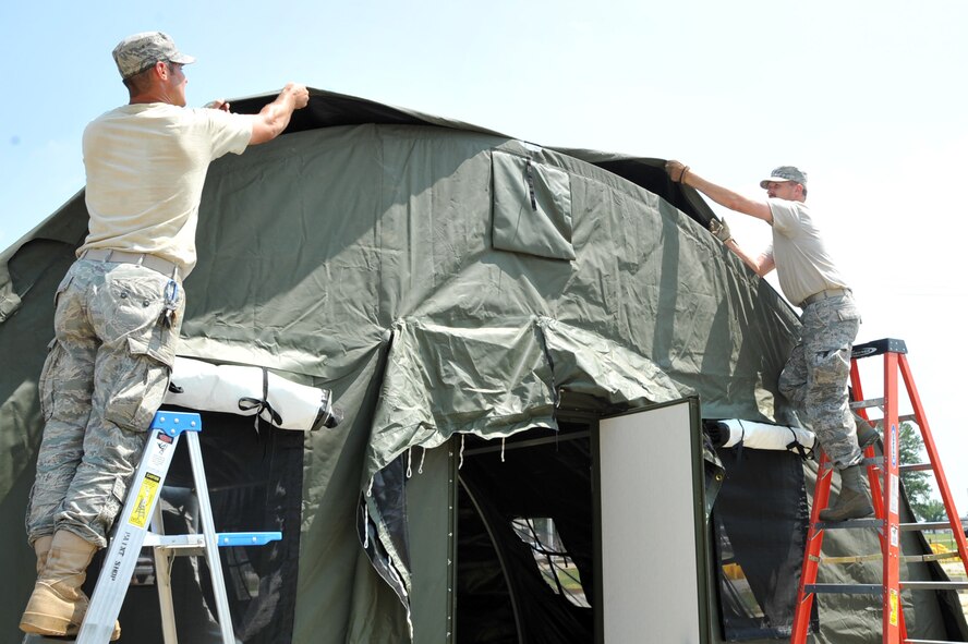 SEYMOUR JOHNSON AIR FORCE BASE, N.C.- Airman 1st Class Kyle Dunkelberg, left, and Master Sgt. Danny Kates pull the outer liner over a rapid deployment system (RDS) tent frame while setting up a tent here July 11, 2011. An RDS is a mobile temporary housing unit in deployed locations. Dunkelberg is a 4th Civil Engineer Squadron electrical systems journeyman and a native of Waddington, N.Y. Kates is a 4th Communications Squadron quality assurance flight chief and a native of Richmond, Ind. (U.S. Air Force photo by Senior Airman Whitney Lambert/Released)