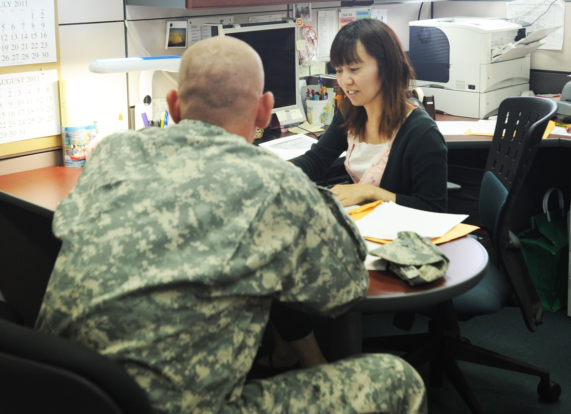 Erika Tamaki, 718th Civil Engineer Squadron housing clerk, processes overseas housing allowance paperwork for a soldier at Kadena's housing office July 19. The 718th CES housing flight manages the largest joint-service housing office in the Defense Department which includes more than 17 dormitories and 8,000 housing units on U.S. installations throughout Okinawa. Tamaki is one of more than 3,000 Japanese employees at Kadena and has worked at the housing flight office for more than eight years. (U.S. Air Force photo/Staff Sgt. Amanda Savannah)