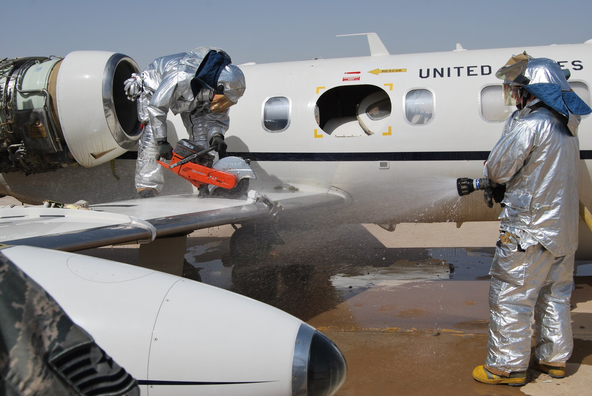 Firefighters from the 407th EOSS cut the wing off a U.S. Air Force C-21 transport aircraft at Contingency Operating Base Adder, Iraq, on July 5.  The aircraft was being dismantled and disposed of, after it was involved in a hard landing in 2009 and deemed irreparable. (Air Force photo by Capt. Jeffrey Davis)