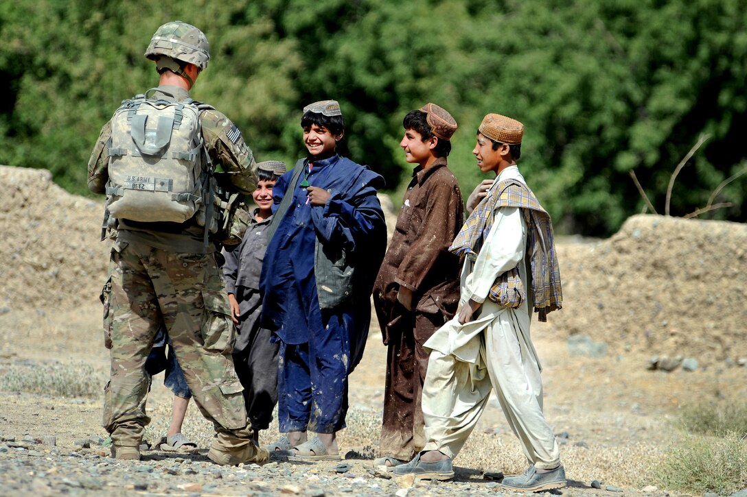 U.S. Army Spc. Anthony Betz talks to local children after patrolling along the Arghandab River in Afghanistan, July 19, 2011. Betz is a medic assigned to Provincial Reconstruction Team Zabul's security force.