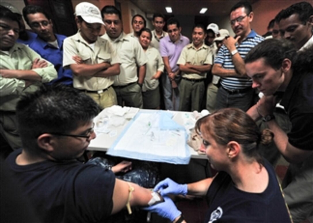 U.S. Navy Lt. Cmdr. Rebecca Pate (right) demonstrates how to insert an IV during a trauma care subject matter expert exchange at Universidad Modular Abierta in Acajutla, El Salvador, during Continuing Promise 2011 on July 19, 2011.  Continuing Promise is a regularly scheduled mission to countries in Central and South America and the Caribbean, where the U.S. Navy and its partnering nations work with host nations and a variety of governmental and nongovernmental agencies to train in civil-military operations.  