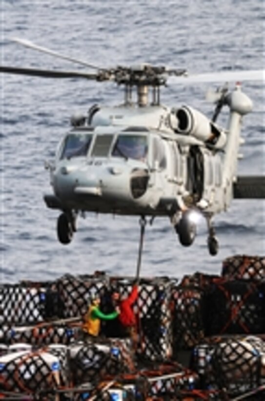 U.S. Navy sailors assigned to the fast combat support ship USNS Bridge (T-AOE 10) attach pallets of cargo to an MH-60S Seahawk helicopter, assigned to Helicopter Sea Combat Squadron 23, during an underway replenishment with the aircraft carrier USS Ronald Reagan (CVN 76) in the Arabian Sea on July 14, 2011.  