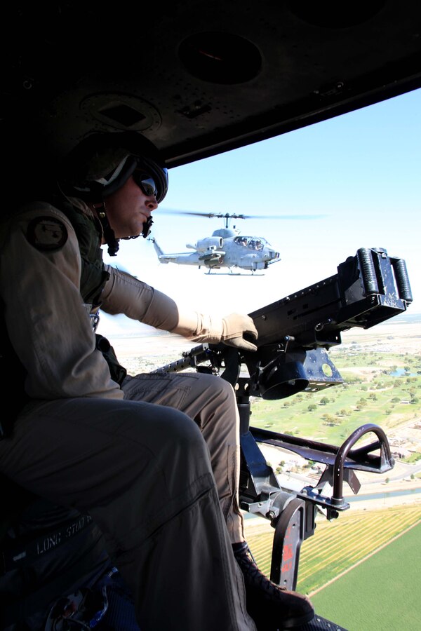 Staff Sgt. Matthew A. Ratliff, HMLA-773 aerial observer, looks out the side of a UH-1N Huey helicopter while an AH-1 Cobra offers aerial support during a close air support exercise at Operation Javelin Thrust July 21. The crew of the Huey eliminated simulated targets with M2 .50-caliber machine gun and M240 machine fire.
