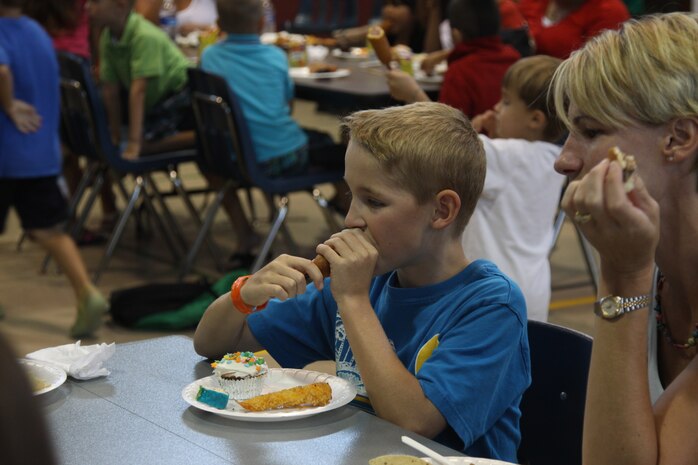 C.J. Czepiel, Summer Enrichment Program participant, takes a bite of a corndog durring the end of Summer Enrichment Program potluck at the Matthew C. Perry Elementary School gym here July 21. The program was a month-long and students learned and attempted to solve some of Earth’s many mysteries.