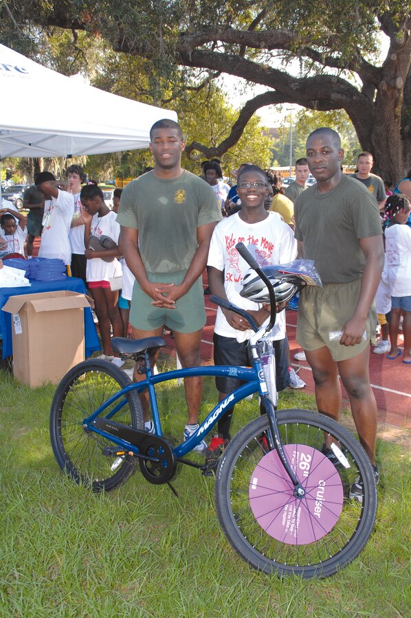 Sgt. Jeffrey Wanliss, left, and Sgt. Matthew Boulden pose with the first-place winner, Janards Stephens, of Kids on the Move. They ran the entire race with the 10-year-old participant.