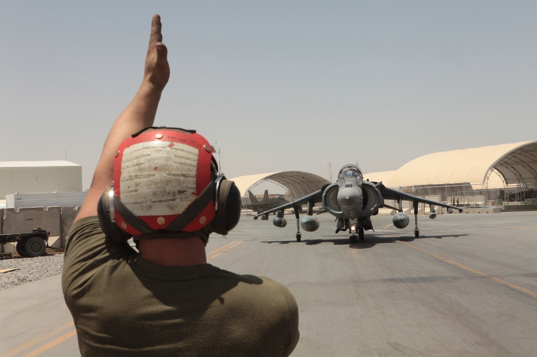 Lance Cpl. Kyle Rowe, a Marine Attack Squadron 513 ordnance technician, signals one of the squadron’s AV-8B Harriers to approach for an arming procedure on the flightline of Kandahar Airfield, Afghanistan, July 22.