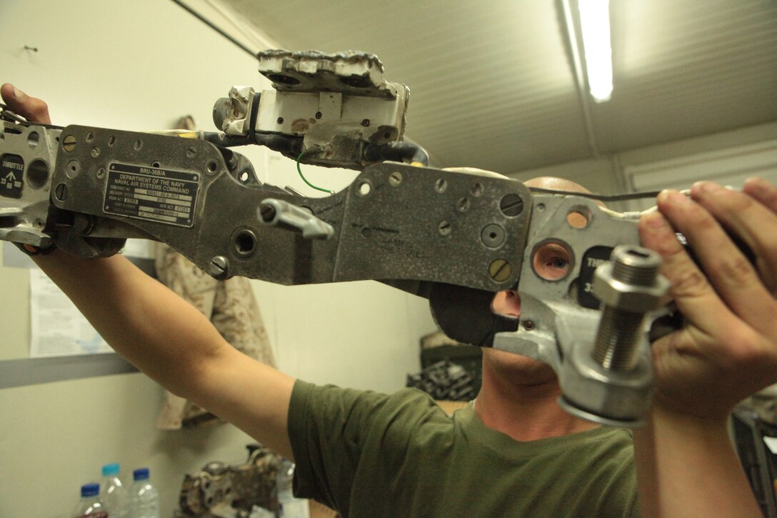 Lance Cpl. Shawn McCarty, a Marine Attack Squadron 513 ordnance technician and Rochelle, Ill., native, inspects a gun rack after cleaning it at Kandahar Airfield, Afghanistan, July 22.