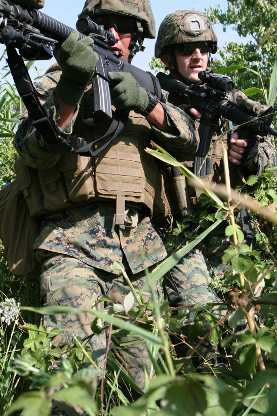 Lance Cpl. Charles Morone and Sgt. Spenser McAvoy, Company A, Anti-Terrorism Battalion, search the bushes for possible insurgents on a training mission here July 22 during Exercise Agile Spirit 2011.  Agile Spirit is designed to increase interoperability between the forces by exchanging and enhancing each other’s capacity in counterinsurgency and peacekeeping operations, including: small unit tactics, convoy operations, and counter-Improvised Explosive Device training.