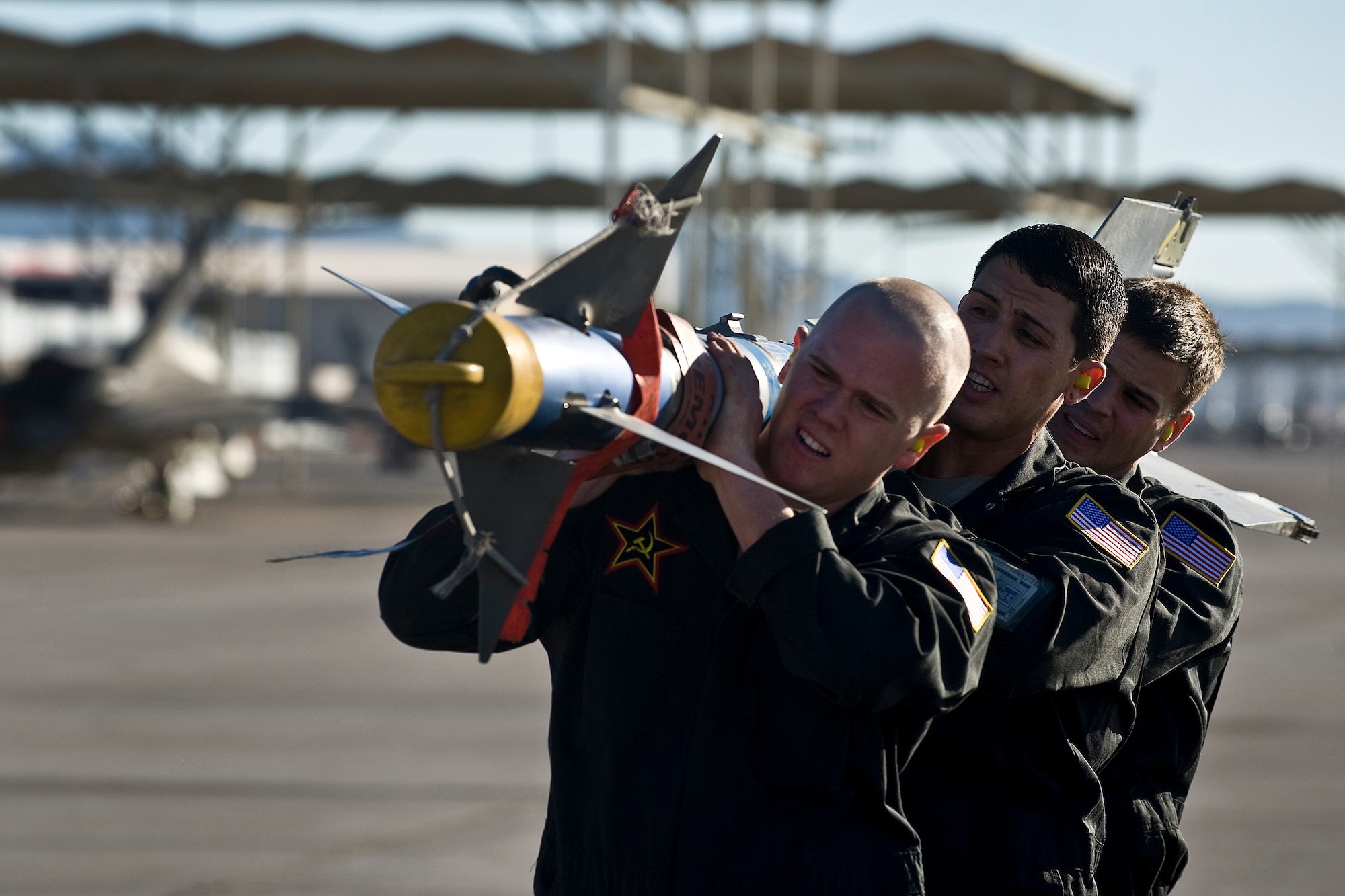 U.S. Air Force Senior Airman Matthew Runnels, Staff Sgt. Beau Ash, and Senior Airman Jeremy Mokler, 757th Aircraft Maintenance Squadron aircraft armament systems Airmen,  carry an AIM-9M Sidewinder air-to-air missile towards a F-15 Eagle during a weapons load crew competition July 22, 2011, at Nellis Air Force Base, Nev. Weapons load crew competitions are conducted quarterly to keep Airmen sharp and recognize superior performers. Teams are evaluated for use of the checklist, safety, and overall speed.  (U.S. Air Force photo by Airman 1st Class George Goslin/Released)  