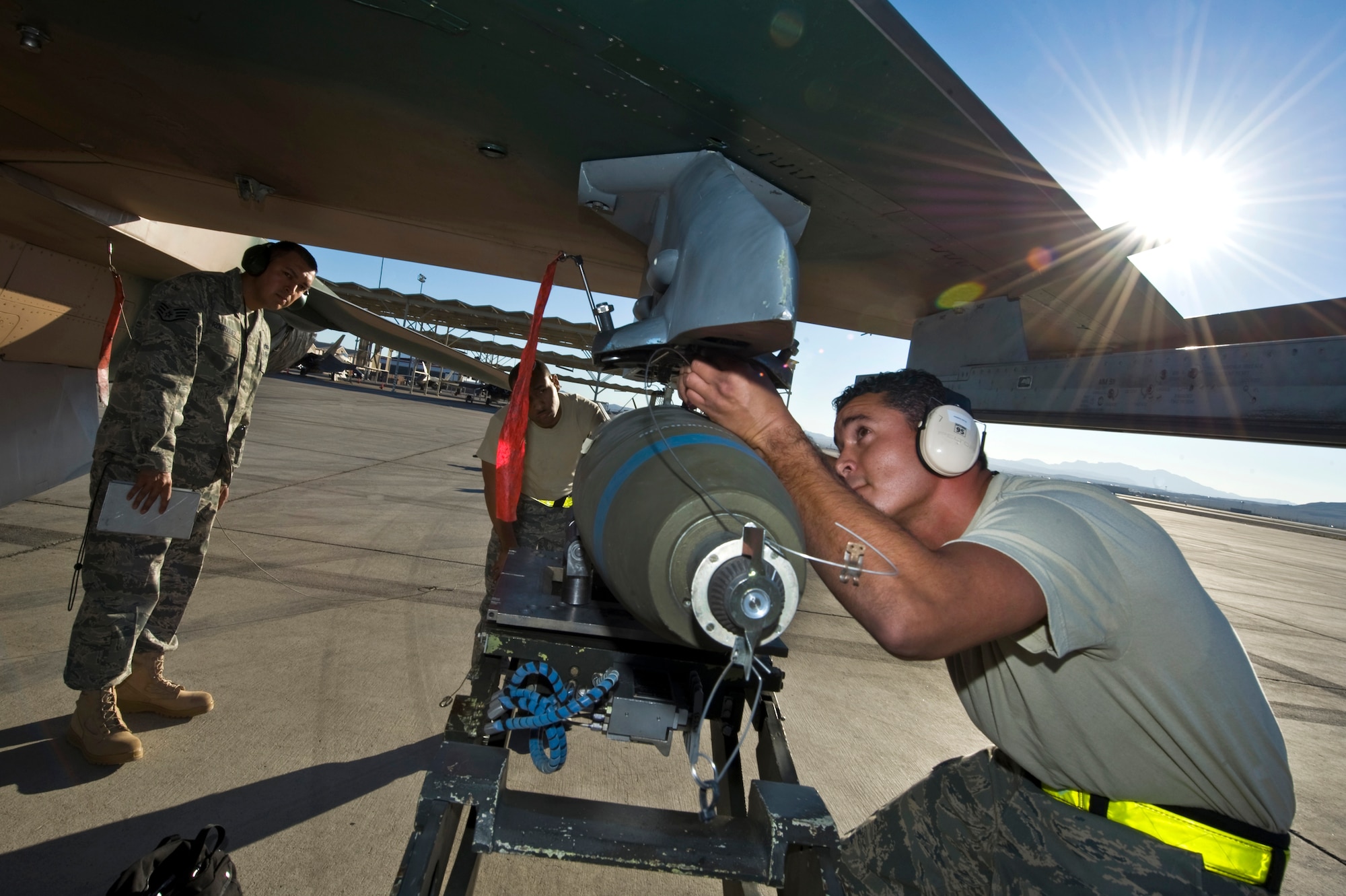 U.S. Air Force Staff Sgt. Robert Rodriguez, 57th Maintenance Squadron aircraft armament systems craftsman, evaluates Staff Sgt. Michael Perera, 929 Aircraft Maintenance Squadron aircraft armament systems craftsman, arms the lanyard attached to the arming solenoid on a Mark-82 bomb placed on a F-16 Fighting Falcon during a weapons load crew competition July 22, 2011, at Nellis Air Force Base, Nev. Weapons load competitions are conducted quarterly to keep Airmen sharp and recognize superior performers. Teams are evaluated for use of the checklist, safety, and overall speed. (U.S. Air Force photo by Airman 1st Class Daniel Hughes/Released)