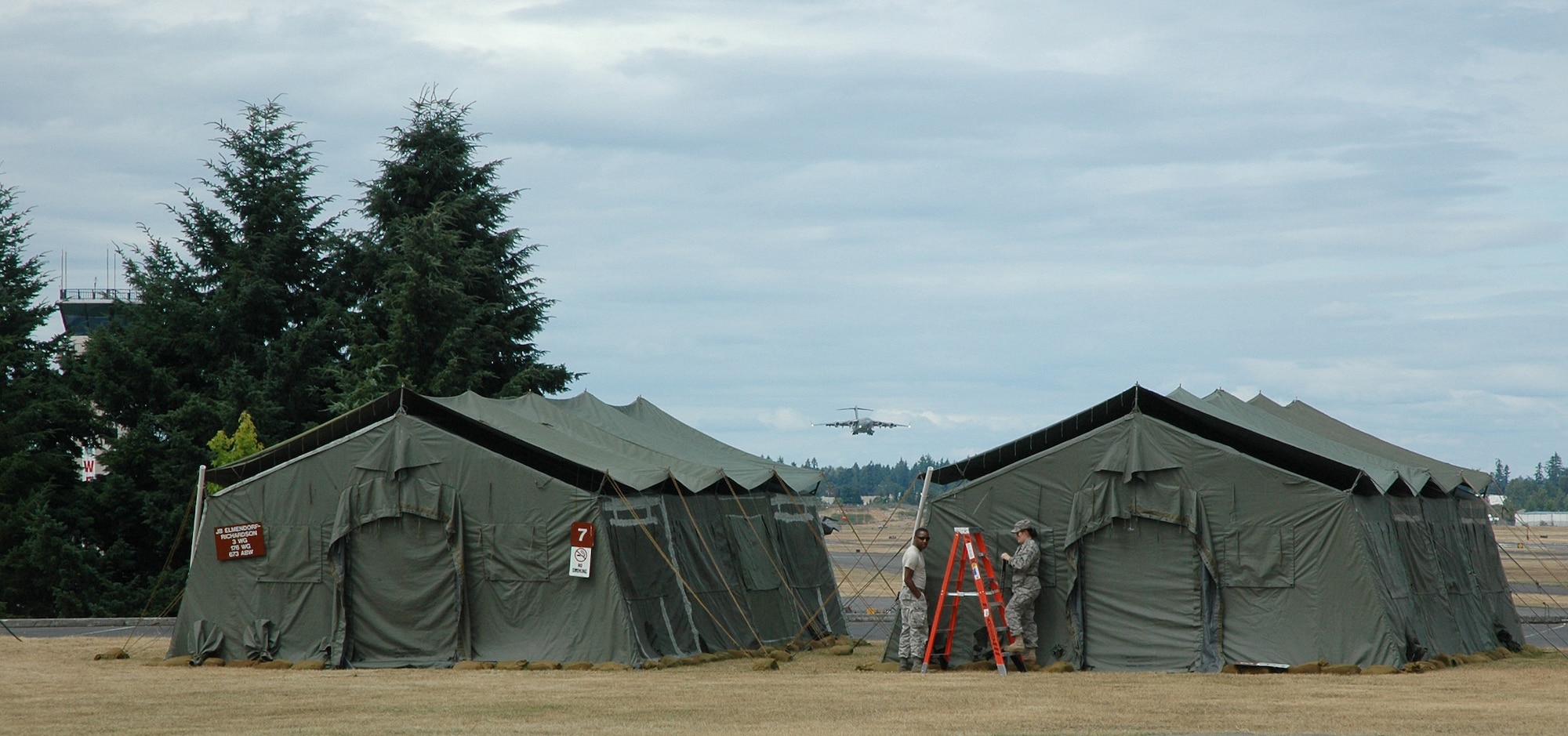 A C-17 arrives at McChord Field, Wash., while Wranglers set up tents to be used by visiting teams during Air Mobility Rodeo here July 24-29. (U.S. Air Force photo by Sandra Pishner)