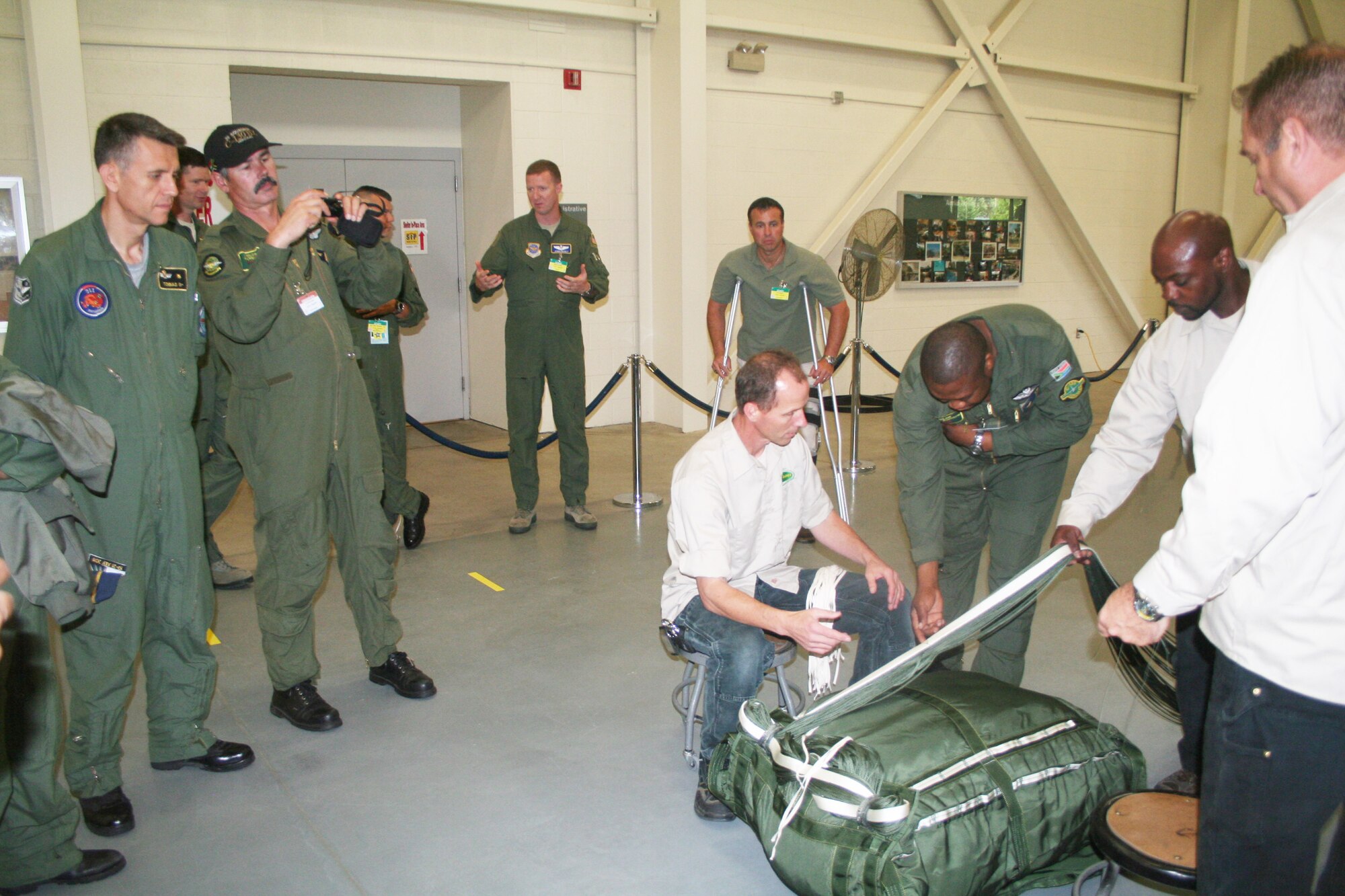 International oberservers watch parachute riggers pack a parachute at the 62nd Aerial Port Squadron aerial delivery facility July 21, 2011, at Joint Base Lewis-McChord, Wash. Participants in the 2011 International Airdrop Symposium stopped at the facility as part of the symposium July 19-21, 2011. (U.S. Air Force Photo/Master Sgt. Scott T. Sturkol)