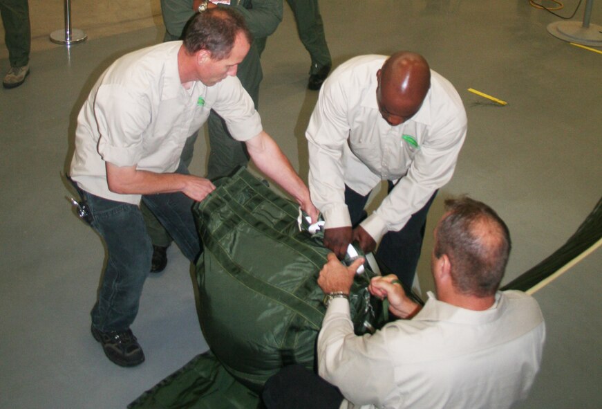 Jay Boison, Romereo Scruggs and Allan Lebleu, parachute riggers at the 62nd Aerial Port Squadron aerial delivery facility, prepare a parachute for an airdrop bundle during operations at the facility July 21, 2011, at Joint Base Lewis-McChord, Wash. Boison, Scruggs, and Lebleu, who work for contractor Trailboss, Inc., are among eight people who operate the facility and prepare airdrop training bundles for the 62nd Airlift Wing's mission. (U.S. Air Force Photo/Master Sgt. Scott T. Sturkol)