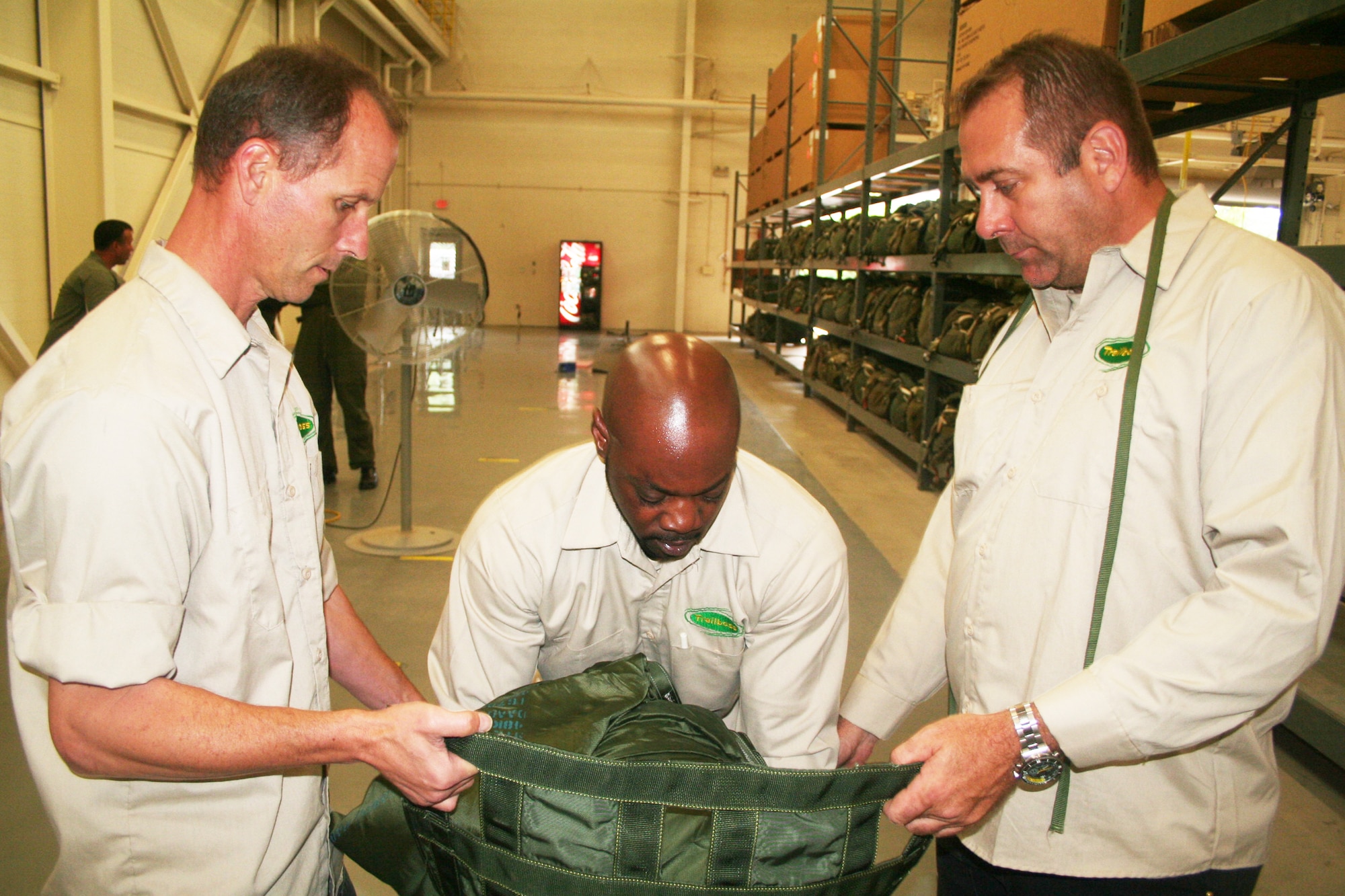 Jay Boison, Romereo Scruggs and Allan Lebleu, parachute riggers at the 62nd Aerial Port Squadron aerial delivery facility, prepare a parachute for an airdrop bundle during operations at the facility July 21, 2011, at Joint Base Lewis-McChord, Wash. Boison, Scruggs, and Lebleu, who work for contractor Trailboss, Inc., are among eight people who operate the facility and prepare airdrop training bundles for the 62nd Airlift Wing's mission. (U.S. Air Force Photo/Master Sgt. Scott T. Sturkol)