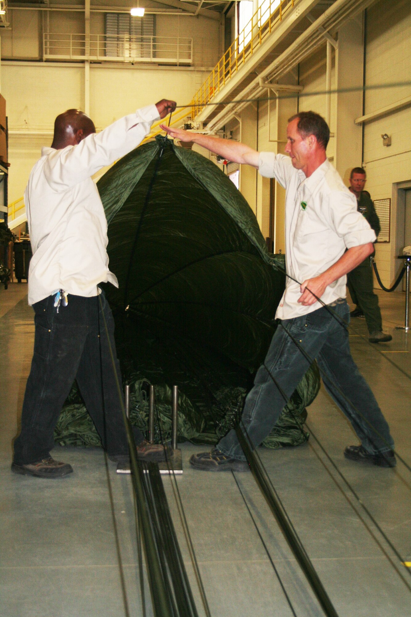Romereo Scruggs and Jay Boison, parachute riggers at the 62nd Aerial Port Squadron aerial delivery facility, prepares a parachute for an airdrop bundle during operations at the facility July 21, 2011, at Joint Base Lewis-McChord, Wash. Scruggs and Boison, who work for contractor Trailboss, Inc., is one of eight people who operate the facility and prepare airdrop training bundles for the 62nd Airlift Wing's mission. (U.S. Air Force Photo/Master Sgt. Scott T. Sturkol)