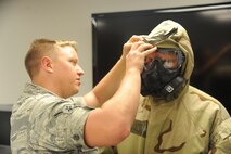 U.S. Air Force Airman Dustin Garner, 23rd Civil Engineer Squadron readiness emergency management, and an exercise evaluation team member demonstrate how to properly secure a gas mask during an ability to survive and operate rodeo training session at Moody Air Force Base, Ga., July 22, 2011. Garner had each member pair up with a partner and perform buddy checks to ensure their gear was worn correctly. (U.S. Air Force photo by Airman 1st Class Paul Francis/Released)