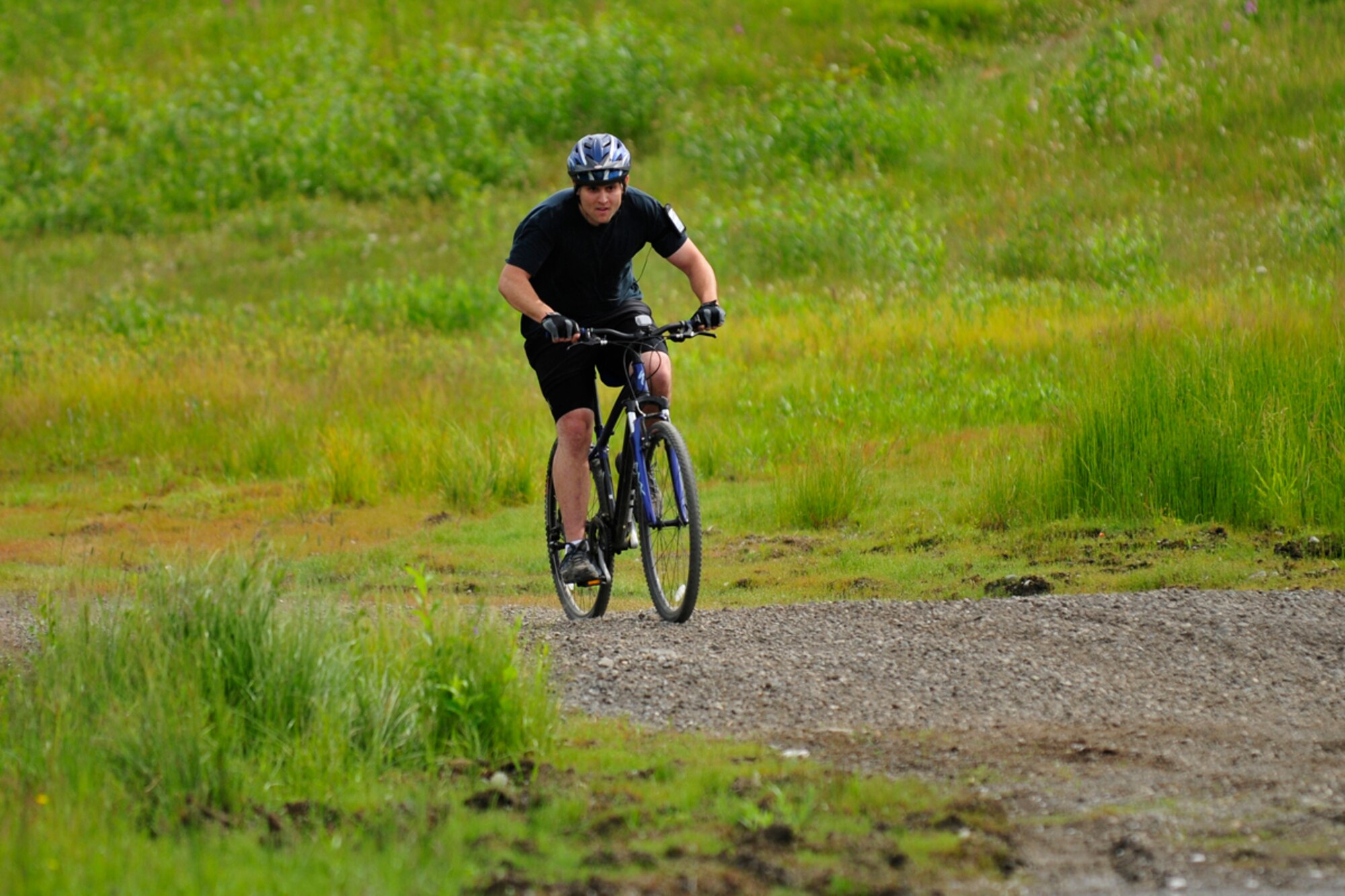 Air  Force Staff Sgt. Andrew Postula of the 3rd Maintenance Squadron brings his bike in to complete his nine-mile ride as part of the challenge.   (U.S. Air Force photo/Steve White)