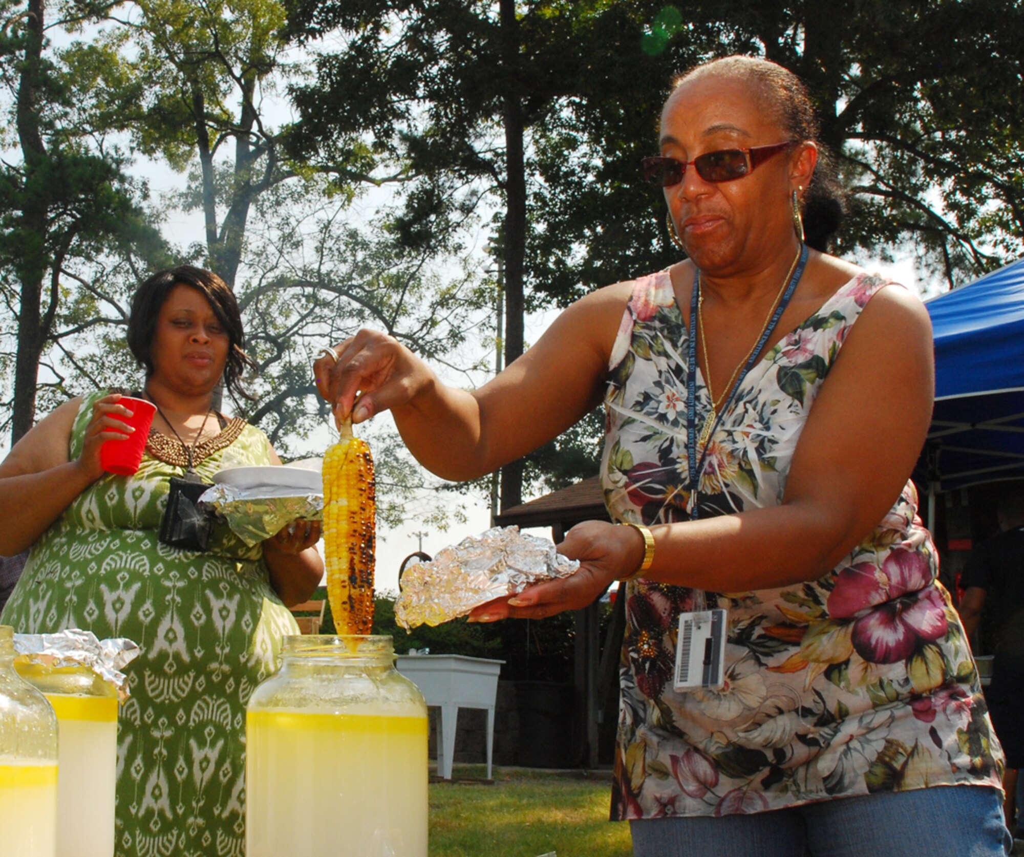 Frances Donner from Dobbins civilian pay, hand dips roasted corn into a jar of melted butter. The 8th annual Corn and Sausage Roast held July 20 includes the seasonal, southern favorite every year. To accompany the fresh corn, attendees also received two bratwurst sausages, a drink and dessert. (U.S. Air Force photo/Airman 1st Class Chelsea Smith