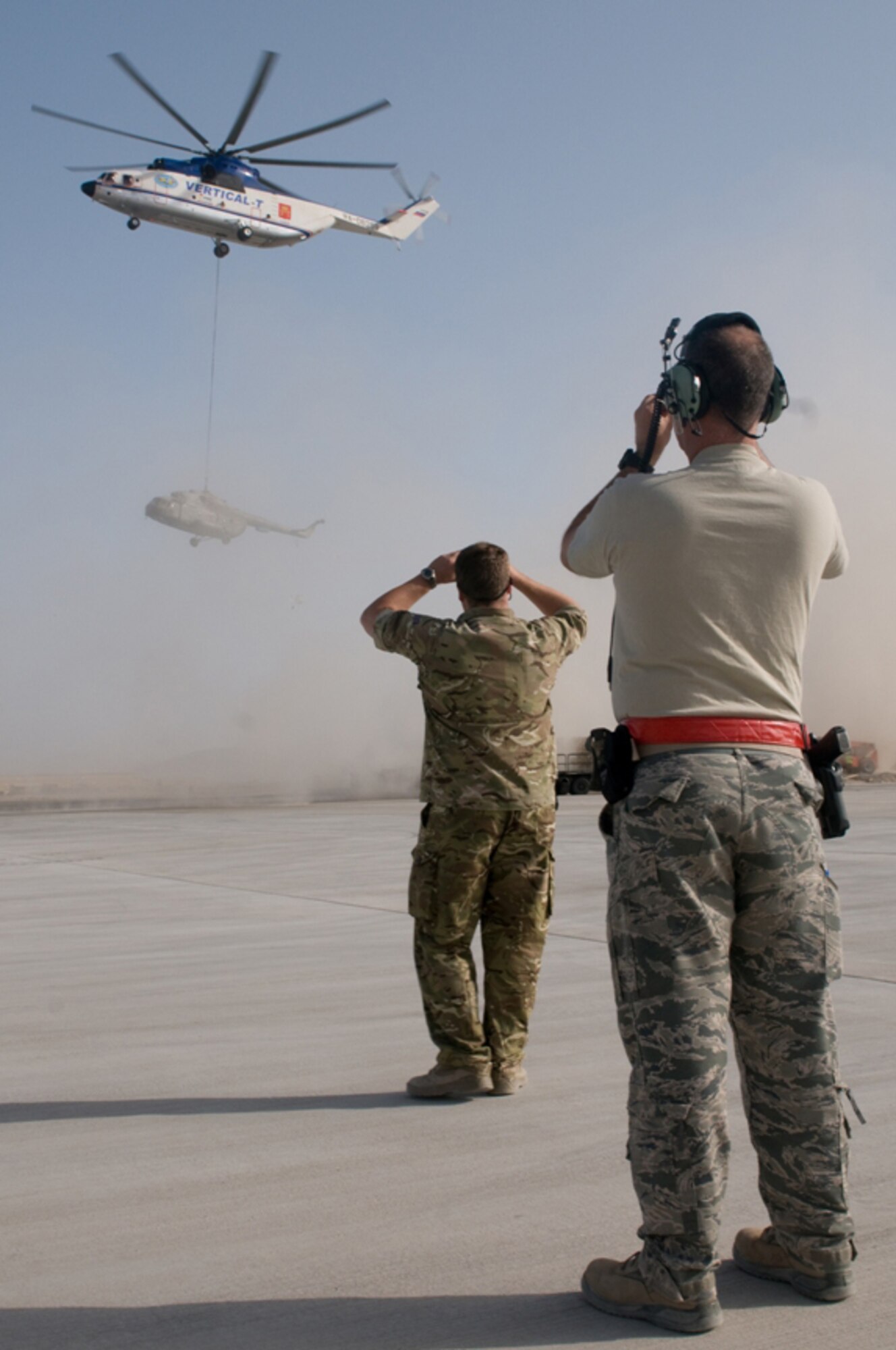 Onlookers watch as a damaged Mi-17 is carried on its way to a repair facility on Kandahar Airfield, Afghanistan on July 13, 2011. The helicopter is owned by the Afghan Kandahar Air Wing. (U.S. Air Force courtesy photo)