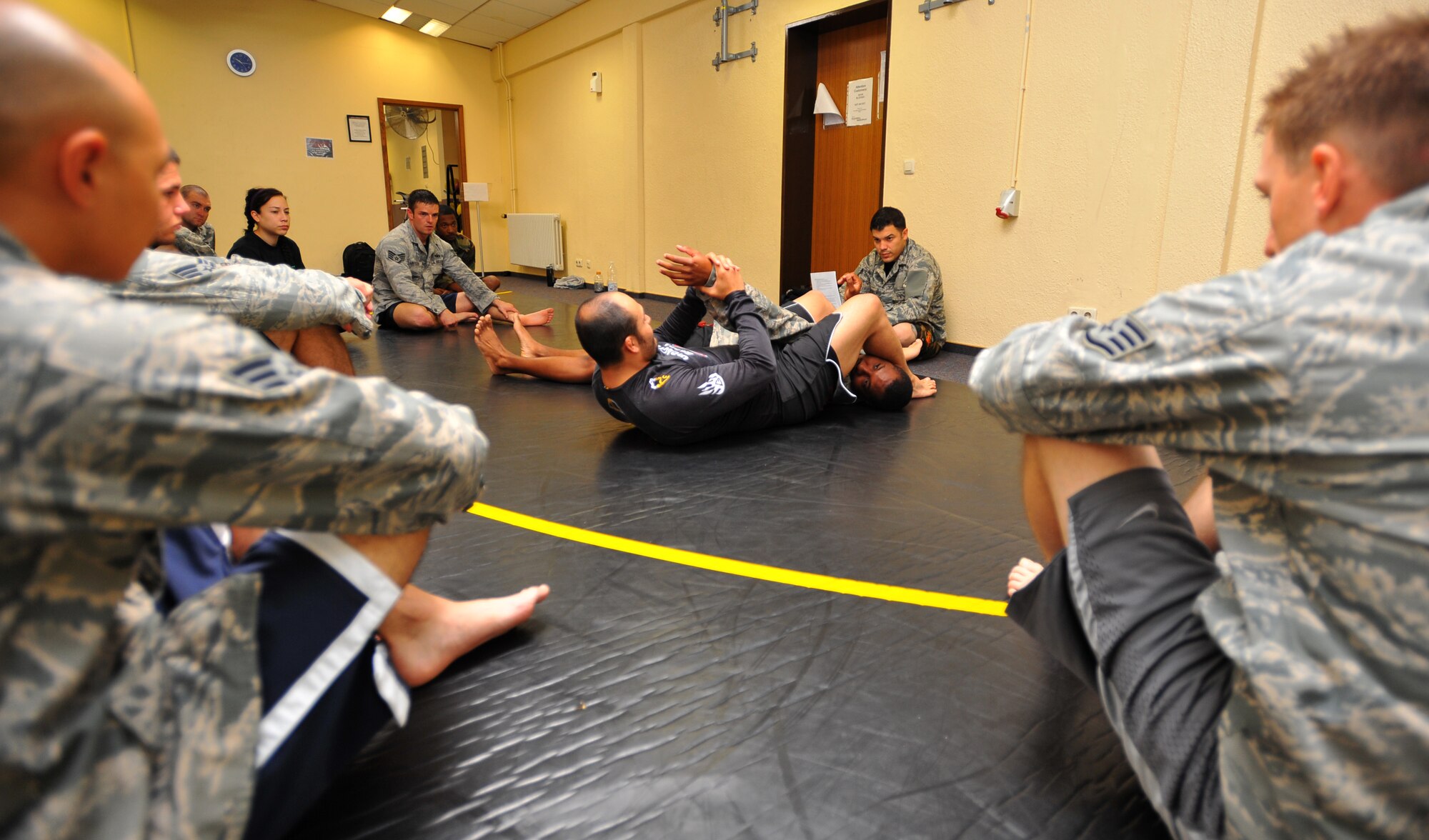 SPANGDAHLEM AIR BASE, Germany – Jesus Carlos, combatives training instructor, center, and Staff Sgt. Cesar Matos, 52nd Security Forces Squadron combatives training instructor, demonstrate proper technique for securing an arm bar during a combatives training class at the Skelton Memorial Fitness Center here July 19. Combatives classes last five days and are free for active-duty military and family members 18 years and older. (U.S Air Force photo/Airman 1st Class Dillon Davis)