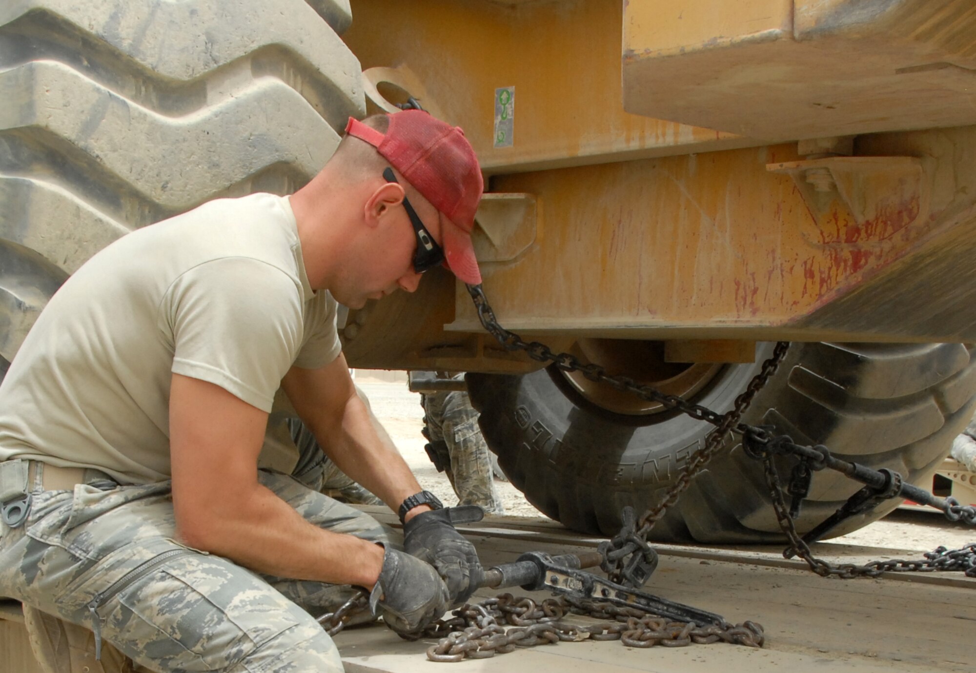 A member of the 809th Expeditionary Rapid Deployable Heavy Operational Repair Squadron Engineers (RED HORSE) in South East Afghanistan chains construction equipment to a truck in preparation to convoy to Kandahar  Airfield July 14, 2011. RED HORSE constructed two runways at a forward operating base. (U.S. Air Force photo by Tech. Sgt. Emily F. Alley)
