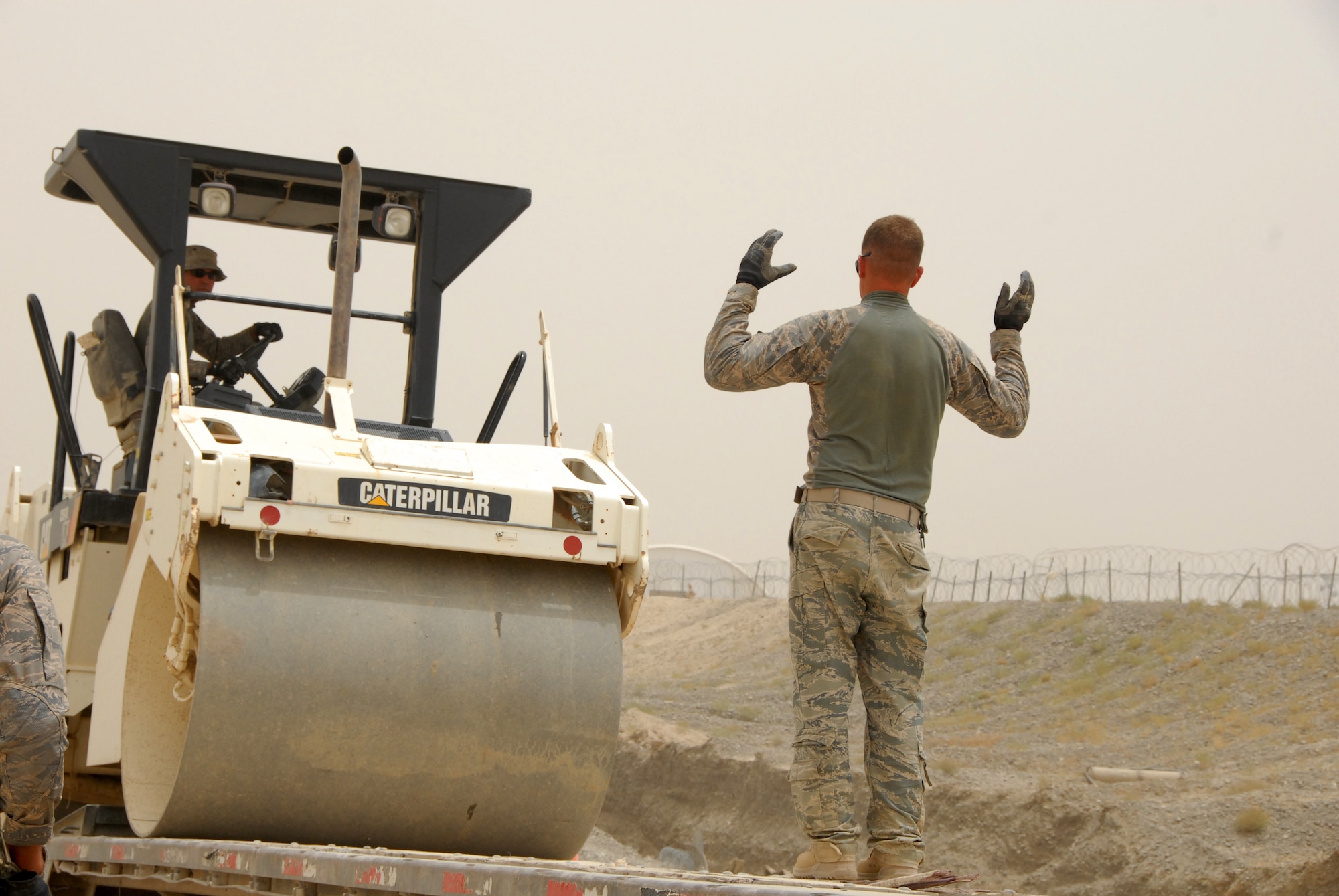 A member of the 809th Expeditionary Rapid Deployable Heavy Operational Repair Squadron Engineers (RED HORSE) in South East Afghanistan directs construction equipment onto a truck in preparation to convoy to Kandahar  Airfield July 14, 2011. RED HORSE constructed two runways at a forward operating base. (U.S. Air Force photo by Tech. Sgt. Emily F. Alley)