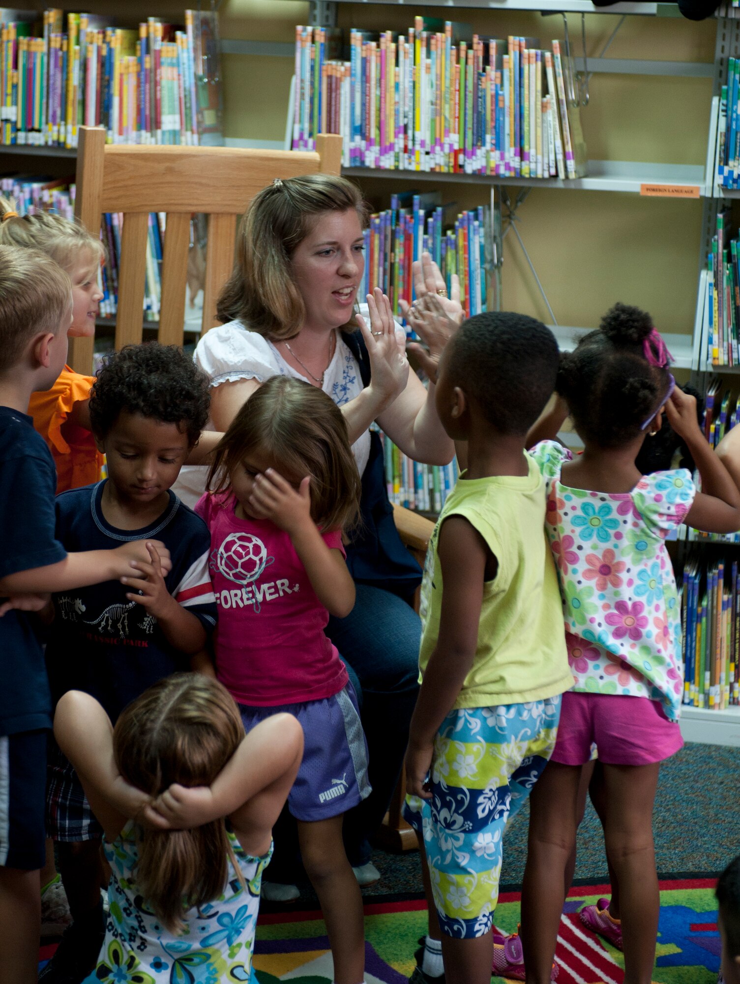 Sara Sesker,39th Force Support Squadron lead technician, high fives a group of 3-5 year olds from the Child Development Center July 22, 2011, at the library at Incirlik Air Base, Turkey.(U.S. Air Force photo by Airman 1st Class Clayton Lenhardt/Released)