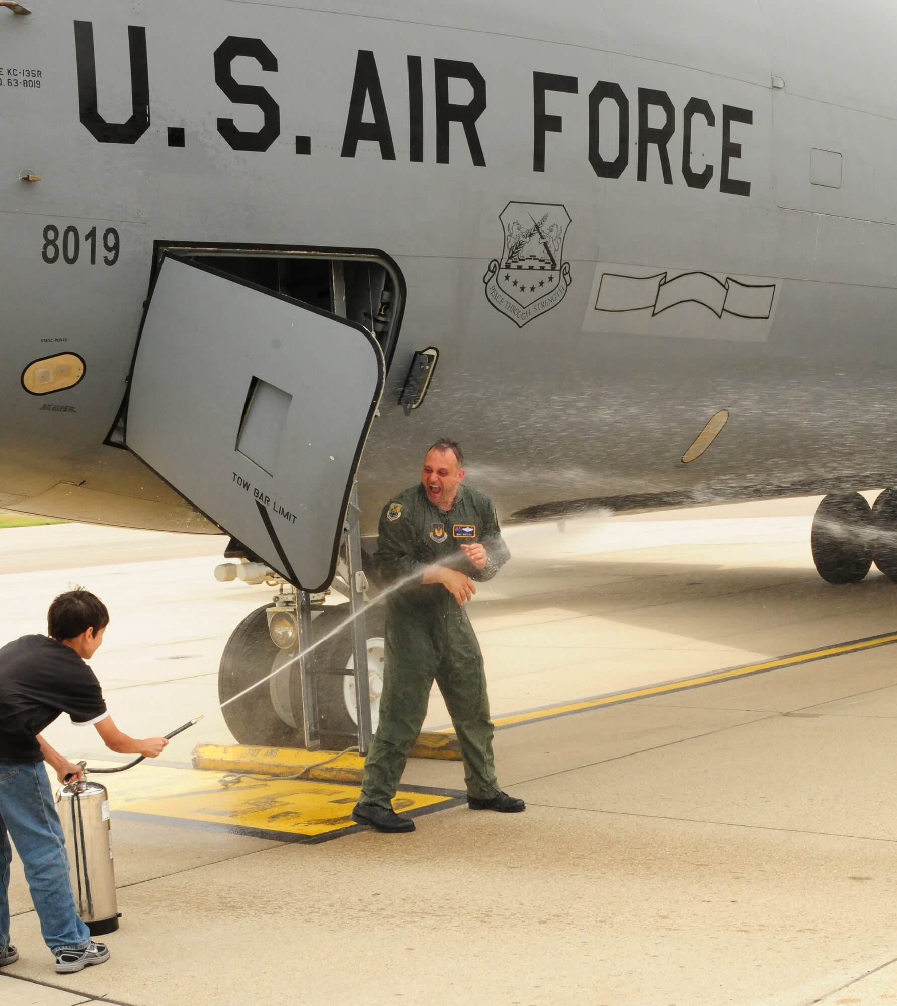 RAF MILDENHALL, England -- Col. Mike Winters, 100th Air Refueling Wing vice commander, gets a soaking from his son, Tim, 12, after finishing his final flight at RAF Mildenhall July 21, 2011. Winters' family -- Rohini (wife), Mike, 14, and Tim (sons), and Sarina (daughter), 6, were at the hardstand to give him the traditional hosing down. His youngest daughter, Ashley, 3, was not at the event. The vice commander is heading to the Pentagon after leaving RAF Mildenhall. (U.S. Air Force photo/Karen Abeyasekere)