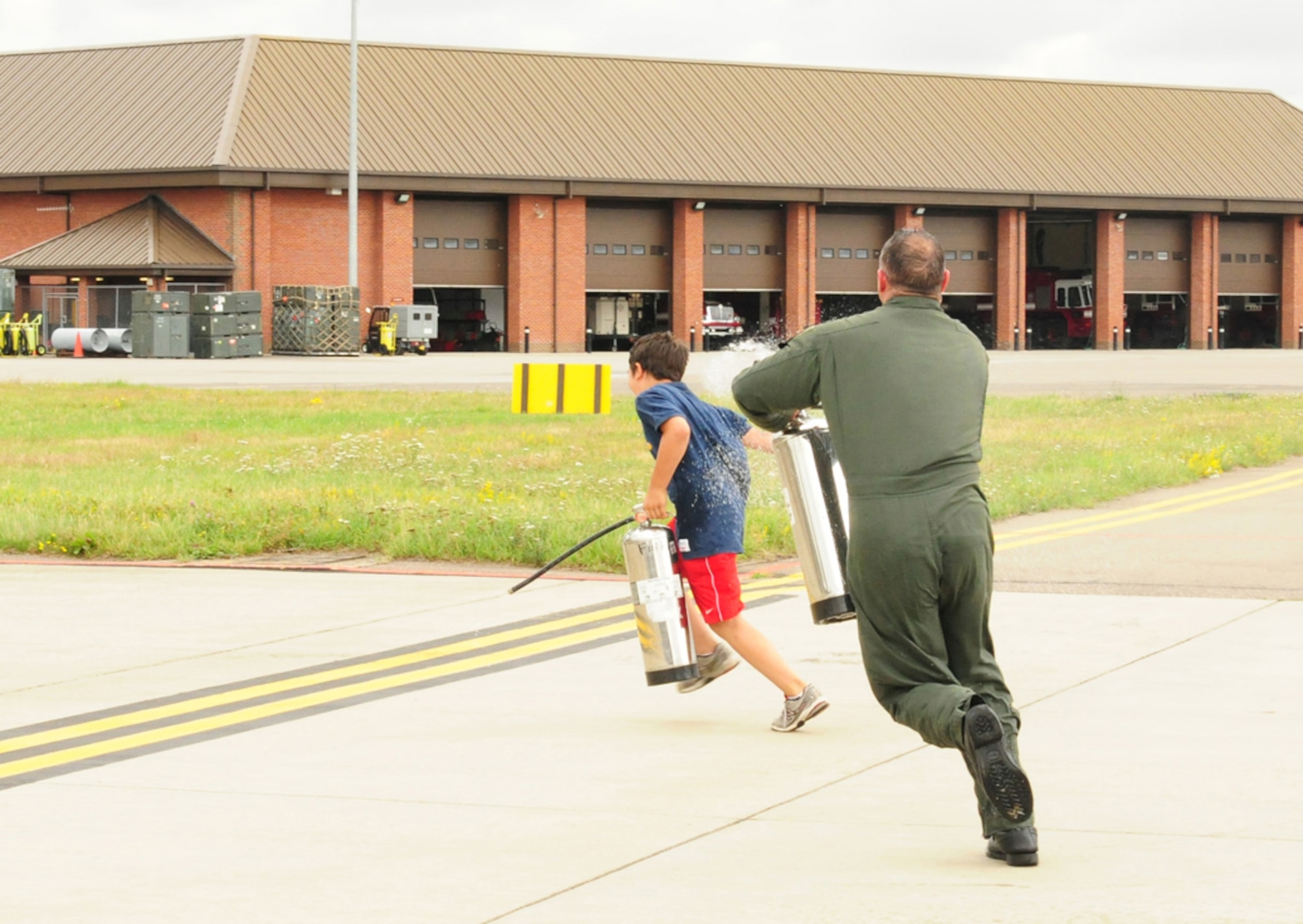RAF MILDENHALL, England -- Col. Mike Winters, 100th Air Refueling Wing vice commander, gets revenge of  his son Tim, 12, after being soaked by a water-filled fire extinguisher following his final flight July 21, 2011. Winters' family -- Rohini (wife), Mike, 14, and Tim (sons), and Sarina (daughter), 6, were out at the jet to welcome him back and give him the traditional soaking. His youngest daughter, Ashley, 3, was not at the event, which was also attended by other base members and leaders. (U.S. Air Force photo/Karen Abeyasekere)