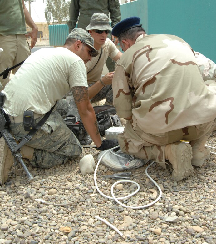 Senior Airman Juan Ramirez and Airman 1st Class Dillon Boutin, both 332nd Expeditionary Civil Engineer Squadron electrical systems journeymen, work with U.S. civilians and Iraqi Airmen to help repair a fountain in front of the Iraqi Air Force Headquarters building at Joint Base Balad, Iraq, July 20. Ramirez is deployed from Andrews Air Force Base, Md., and is a native of Las Vegas, Nev., and Boutin is deployed from Altus AFB, Okla., and is a native of Layfayette, La. (U.S. Air Force photo by Senior Airman Amber R. Kelly-Herard)