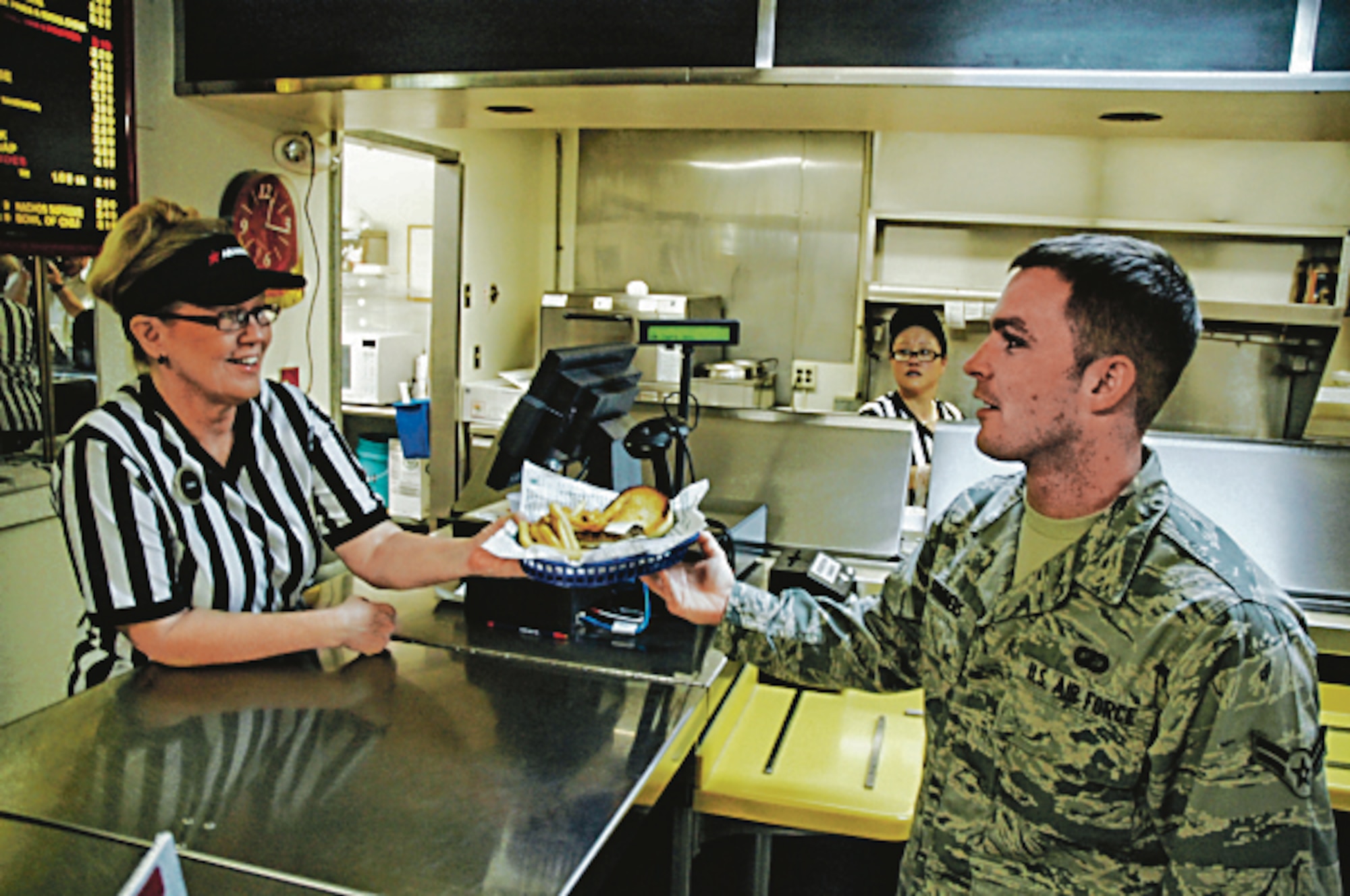 PATRICK AIR FORCE BASE, Fla. -- Airman 1st Class Jackie Summers, 45th Comptroller Squadron, gets lunch from Cheri Heywood, Aramark employee, July 7 at Rocket Lanes Bowling Center under the newly initiated campus style dining program.  Airman who are on meal card status are able to use their Common Access Cards for meals at 45th Force Support Squadron nonappropriated fund dining venues: Beach House, Manatee Cove Golf Course Clubhouse, Rocket Lanes Bowling Center, and The Tides, in addition to Riverside Dining Facility. (U.S. Air Force photo/Eric Brian)