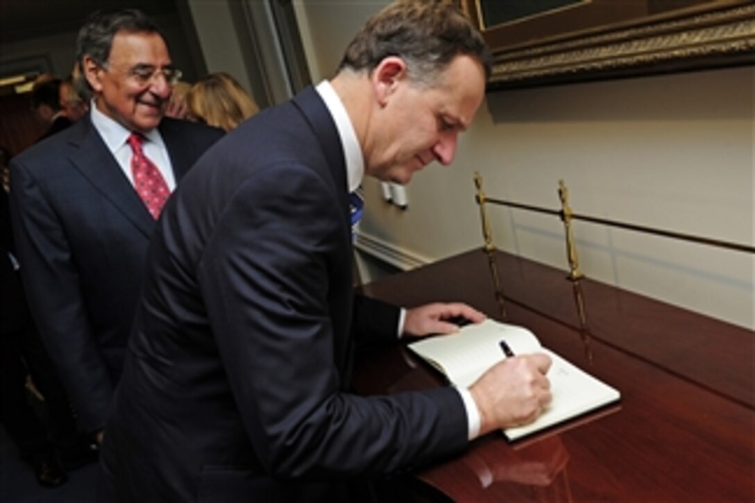 Secretary of Defense Leon E. Panetta looks on as New Zealand Prime Minister John Key signs an official guest book before a meeting in the Pentagon on July 21, 2011.  