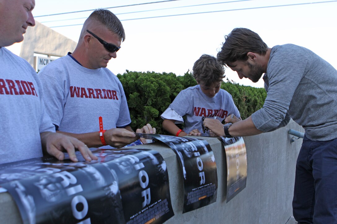 Joel Edgerton, star of the movie "Warrior," an inspirational action drama packed with mixed martial arts, sign autographs for Camp Pendleton service members and their families at the movie screening held at the base theater, July 22. Stars of the movie Tom Hardy, Joel Edgerton, Jennifer Morrison and Kurt Angle were on hand to introduce the film and meet the fans at the sneak-peak viewing, several weeks before its official release date of Sept. 8.