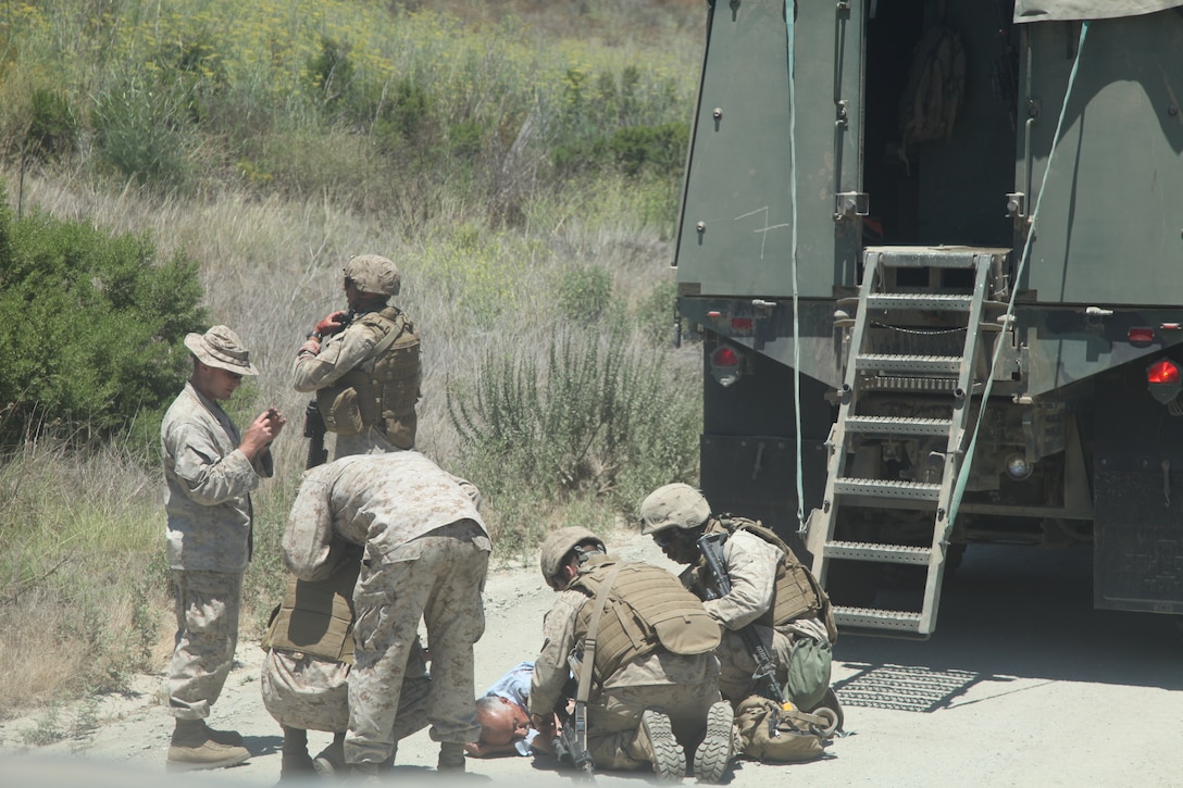 Marines with Motor Transport Company, Combat Logistics Battalion 11, Combat Logistics Regiment 17, 1st Marine Logistics Group, assess a simulated wounded civilian, portrayed by a role-player, during a combat skills training exercise at Camp Pendleton, Calif., July 22. The purpose of the training was to give the Marines an opportunity to see first-hand what they might experience during deployment.