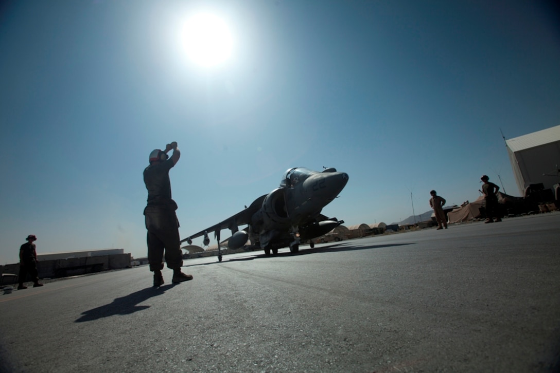 Cpl. Reid Dawson, a Marine Attack Squadron 513 ordnance technician and Broken Arrow, Oklahoma, native, signals one of the squadron’s AV-8B Harriers to approach for an arming procedure on the flightline of Kandahar Airfield, Afghanistan, July 23.