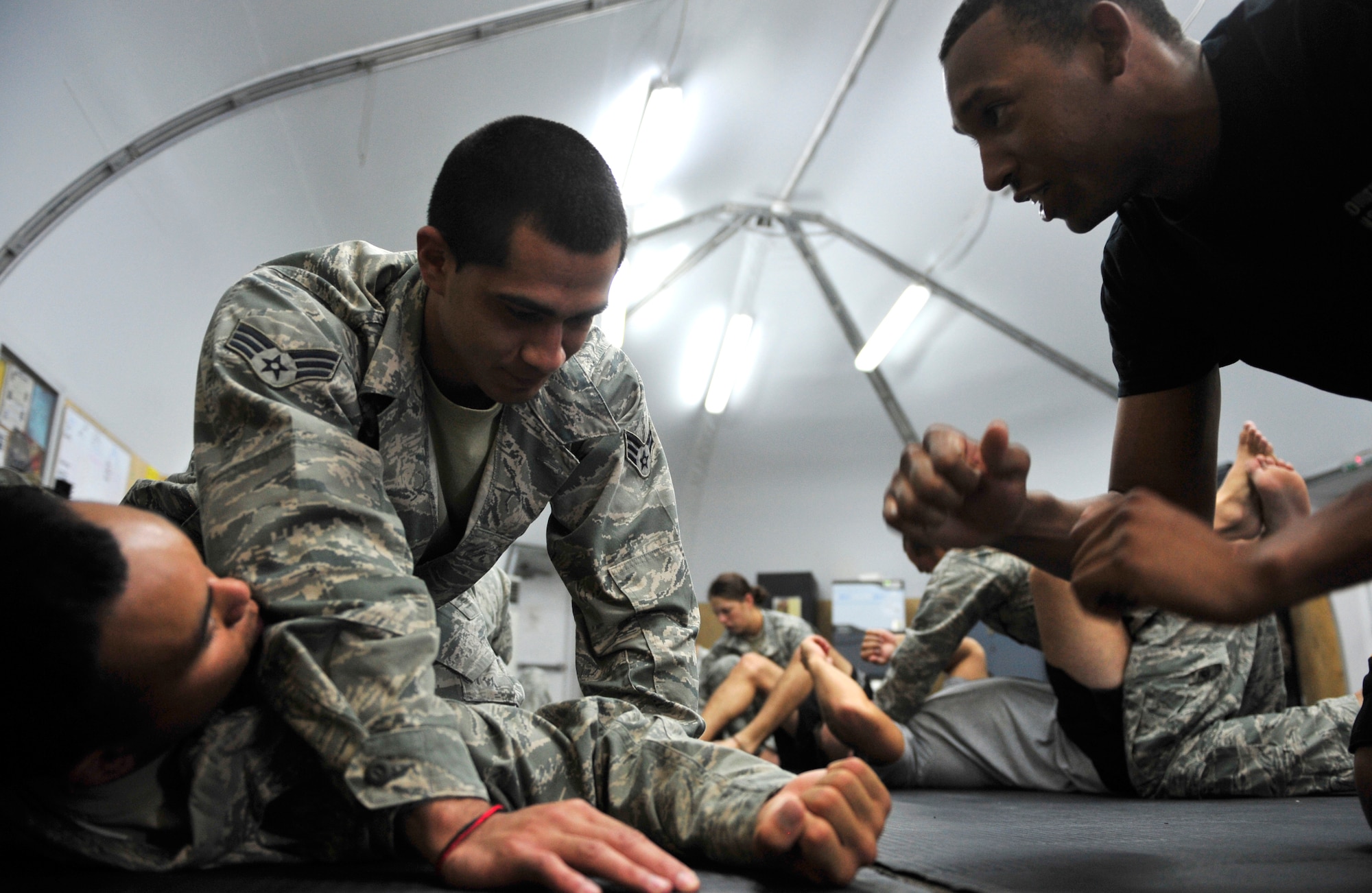 Army Sgt. Anthony King, the assistant instructor for a weeklong Modern Army Combatives Program course, instructs a group of deployed Airmen and Soldiers at the 380th Air Expeditionary Wing in Southwest Asia. King was one of the of the Army-certified MACP instructors who gave the group a week's worth of grappling, arm bars and choke-holds in the process of teaching the level-one certification course. King is a patriot system maintainer for the 3rd Battalion, 4th Air Defense Artillery Regiment deployed from Fort Bragg, N.C. (U.S. Air Force photo/Staff Sgt. Patrick Mitchell)