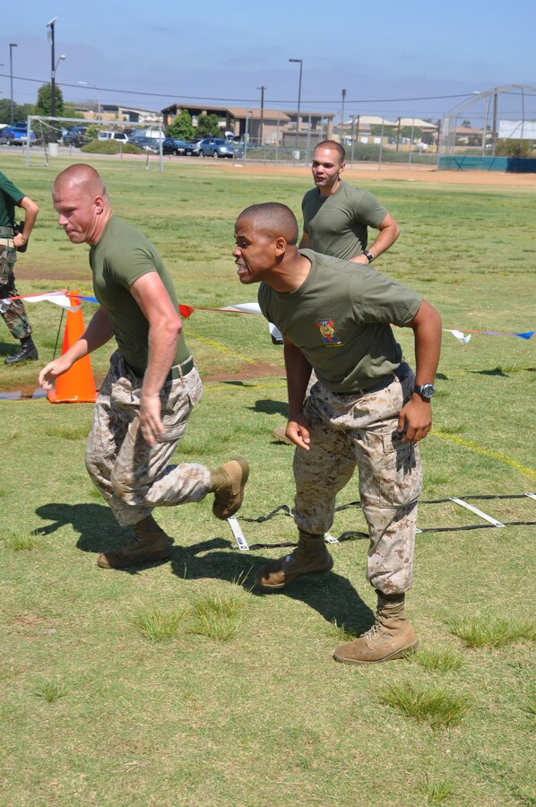 Private First Class Stacey O. Clark, an administrative clerk at Headquarters Battalion, Marine Corps Logistics Base Barstow and a Baltimore native (right), motivates a Marine from Marine Corps Air Station Miramar during the Big Marine, little marine competition July 23.::r::::n::