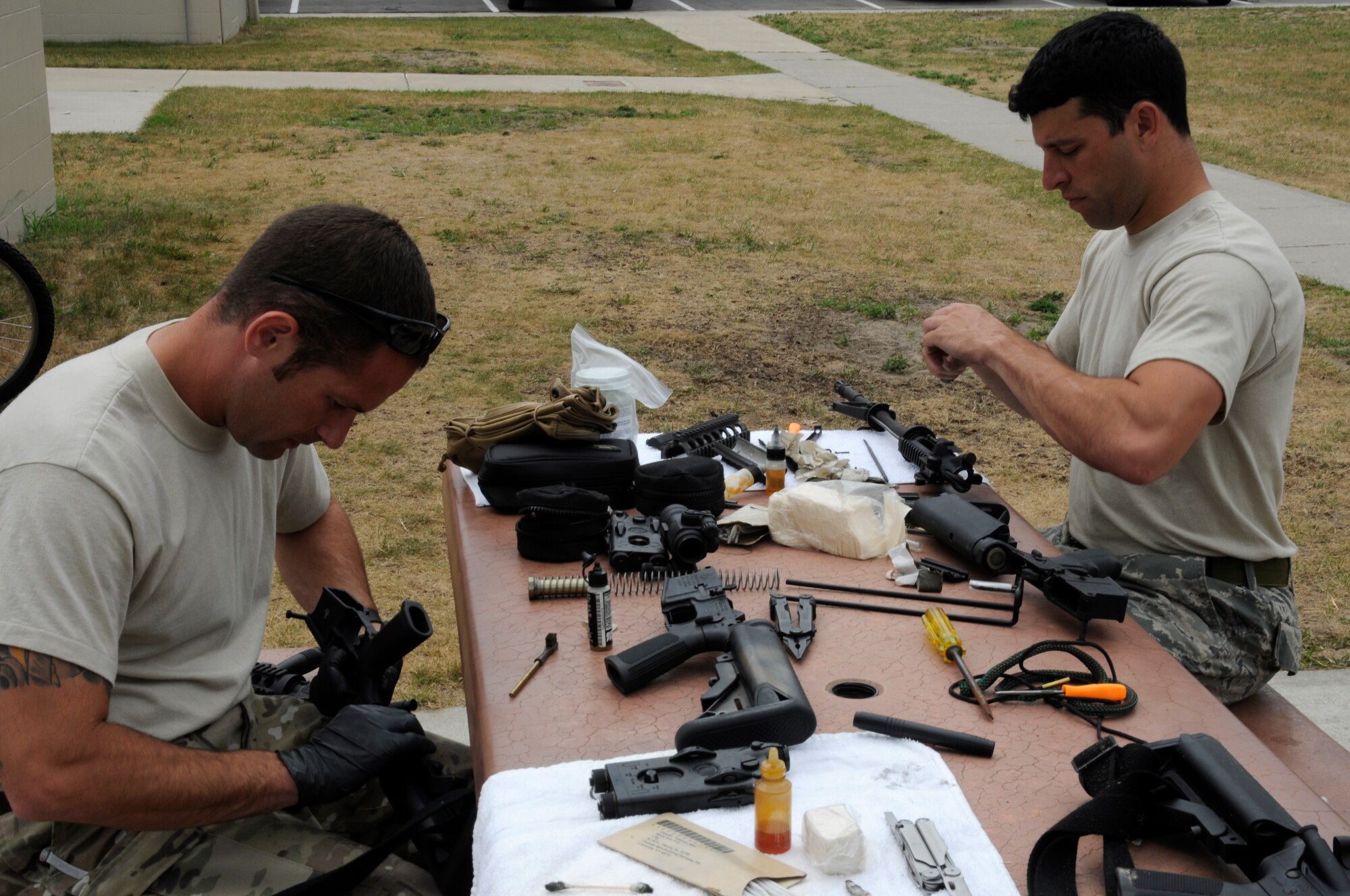 Technical Sgt. Lyle Black and Staff Sgt. Brian Glynn from Selfridge Air National Guard Base, 107th Weather Flight, disassemble their M-4 rifles for cleaning after a day on the shooting range during the annual Gray Wolverine training exercise held at Combat Readiness Training Center Alpena Michigan, July 24, 2011. Black and Glynn regularly disassemble and reassemble their weapons for cleaning to keep them in proper working order. (U.S. Air Force photo by TSgt David Kujawa)
