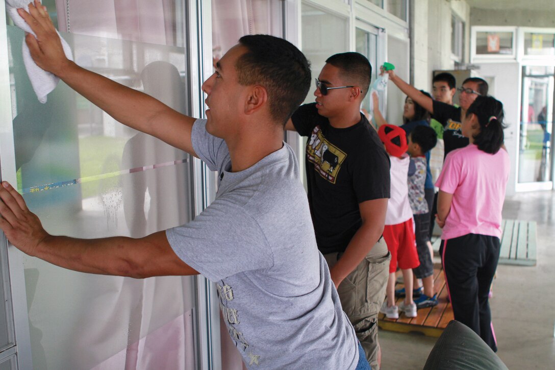 Marines with Headquarters and Headquarters Squadron, Marine Corps Air Station Futenma, wipe down windows alongside residents from Chuo-Ikusei-En in Urasoe City July 25. The Marines were part of a volunteer group that went to the home to lend a hand with daily maintenance.