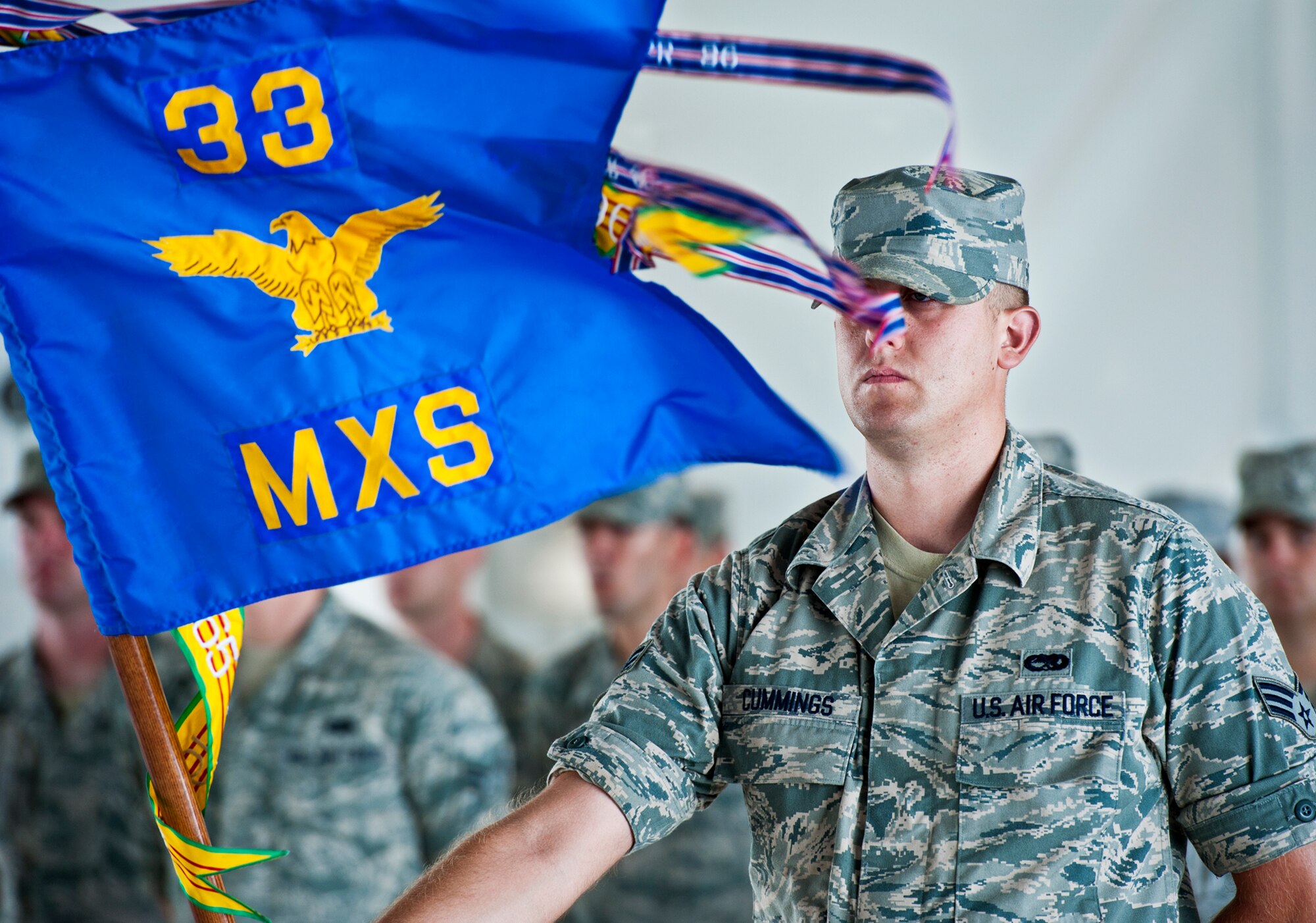 Senior Airman Shaun Cummings holds the 33rd Maintenance Squadron guidon during the 33rd Maintenance Group change of command ceremony July 22 at Eglin Air Force Base, Fla.  Col. Mark Fluker took command of the group from Marine Col. Laura Sampsel.  (U.S. Air Force photo/Samuel King Jr.)