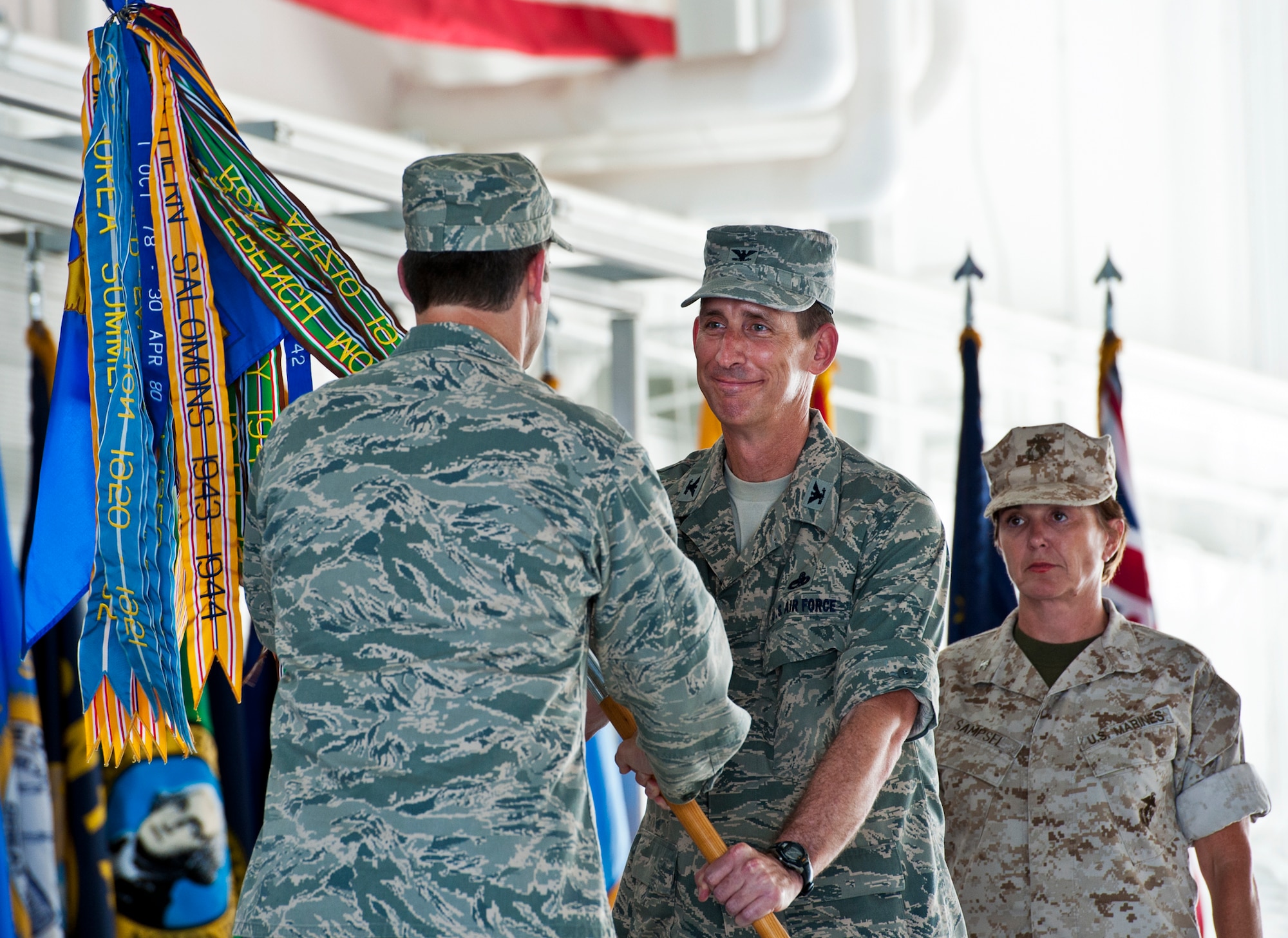 Col. Mark Fluker accepts the 33rd Maintenance Group guidon from Col. Andrew Toth, the 33rd Fighter Wing commander, during the group’s change of command ceremony July 22 at Eglin Air Force Base, Fla.  Marine Col. Laura Sampsel, who relinquished command, stands behind.  (U.S. Air Force photo/Samuel King Jr.)