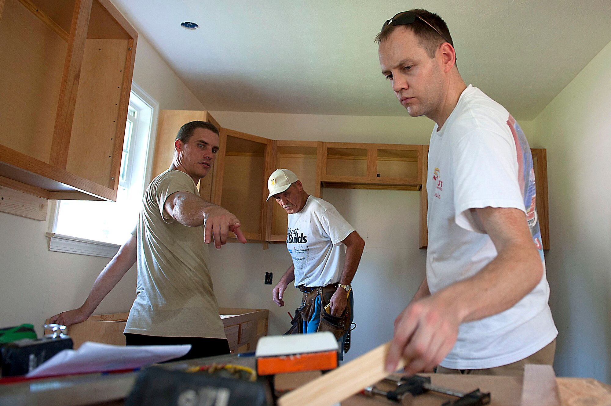 Capt. Travis Passey, 94th Fighter Squadron F-22 Raptor pilot, motions for equipment from Capt. Eddie Cannon, 94th FS F-22 Raptor pilot, while building a house in Newport News, Va., July 21, 2011. More than 20 Airmen from the 1st Fighter Wing volunteered for Habitat for Humanity in efforts to aid the local community.  (U.S. Air Force photo by Airman 1st Class Kayla Newman/Released)