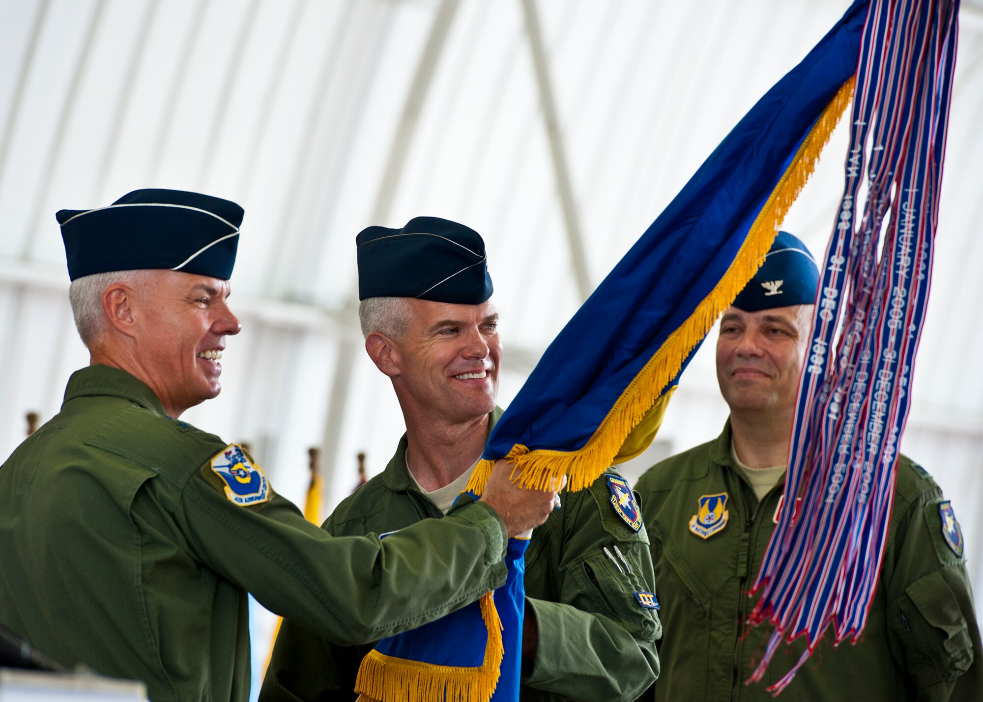 Col. Colin Miller accepts the 46th Test Wing guidon as the new commander from Maj. Gen. C.R. Davis, the Air Armament Center commander, during a change of command ceremony July 22 at Eglin Air Force Base, Fla.  Col. Michael Brewer, who relinquished command, stands behind. (U.S. Air Force photo/Samuel King Jr.)  